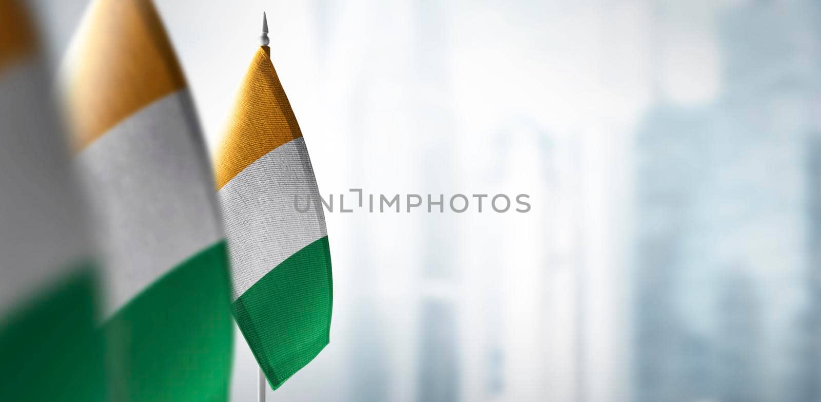 Small flags of Cote dIvoire on a blurry background of the city.