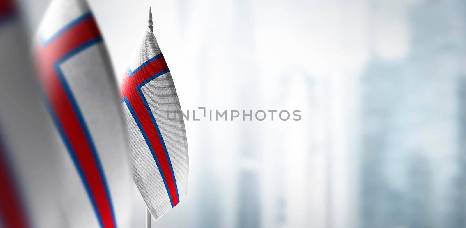 Small flags of Faroe Islands on a blurry background of the city.