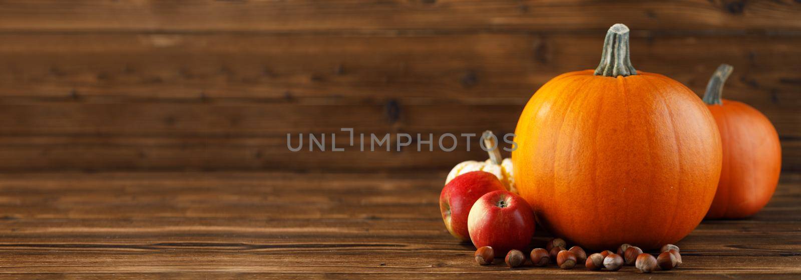 Wood background with pumpkins, apples and nuts. Copy space for text