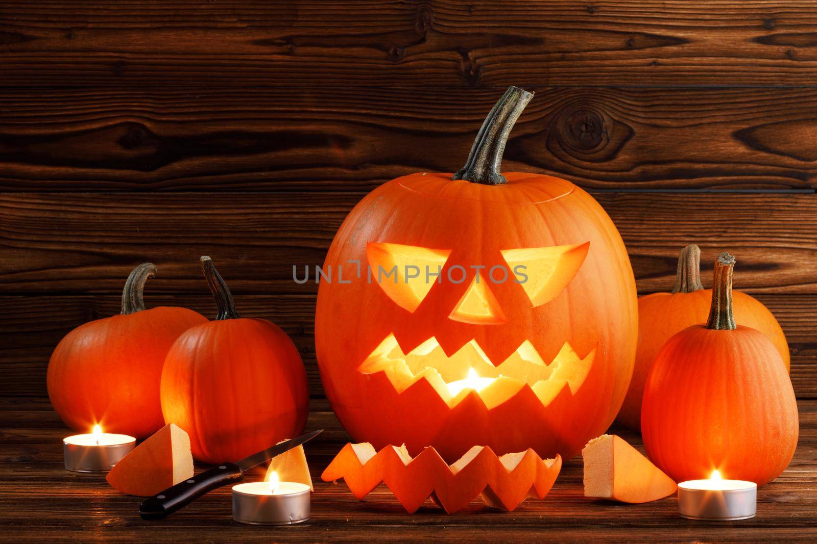 Carving of Halloween pumpkin in progress, candles pieces and cutting knife on wooden background