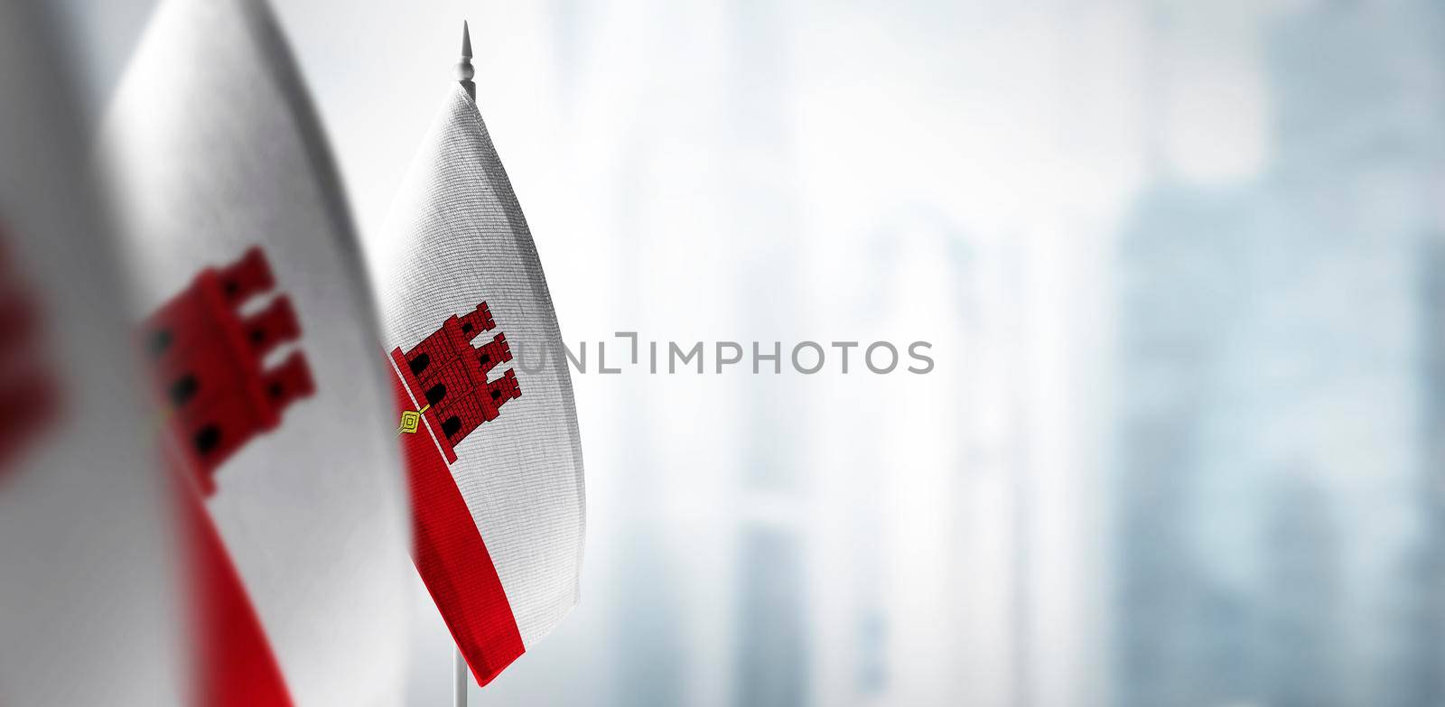Small flags of Gibraltar on a blurry background of the city.