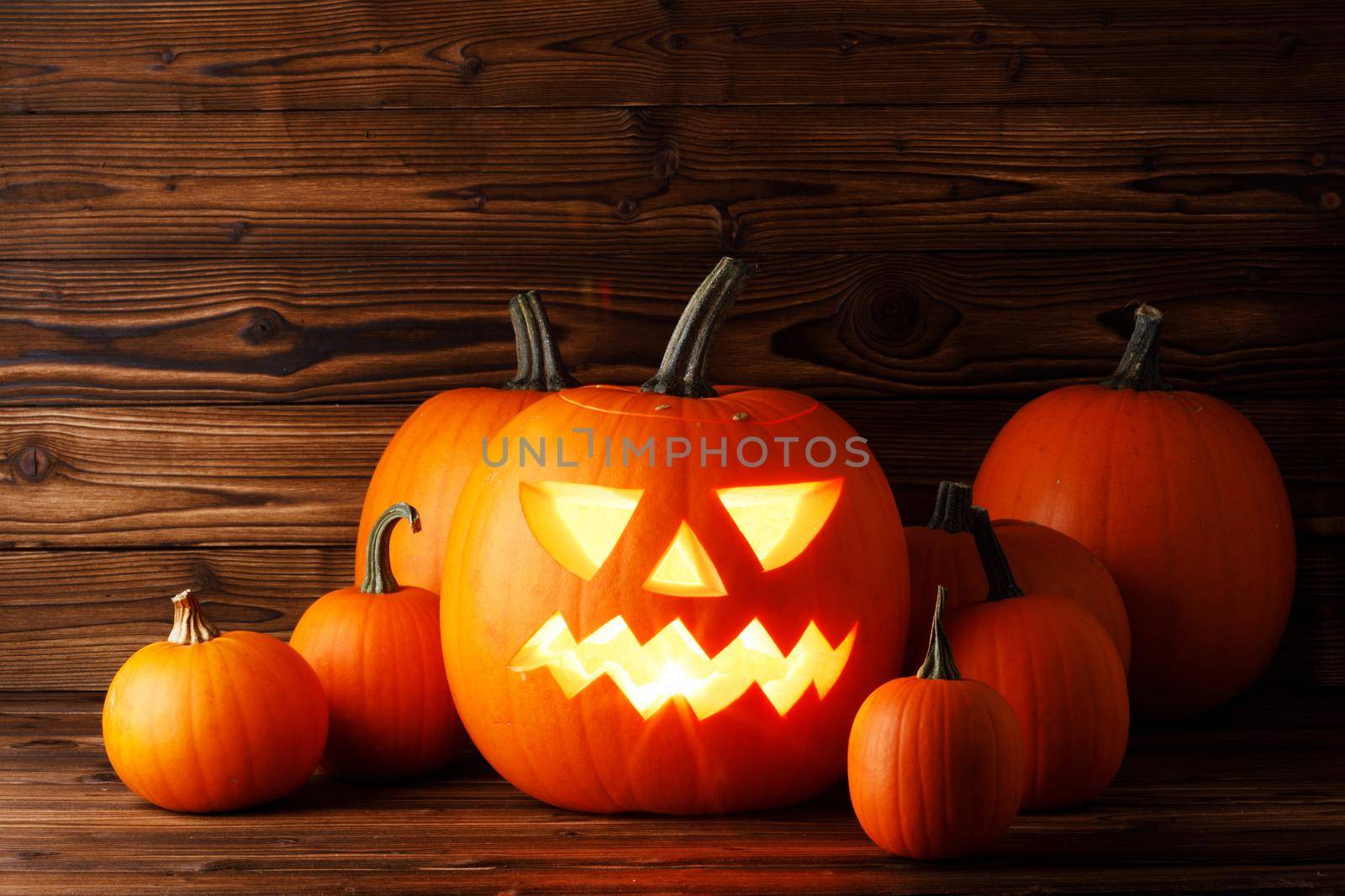 Glowing Halloween pumpkins on old wooden background