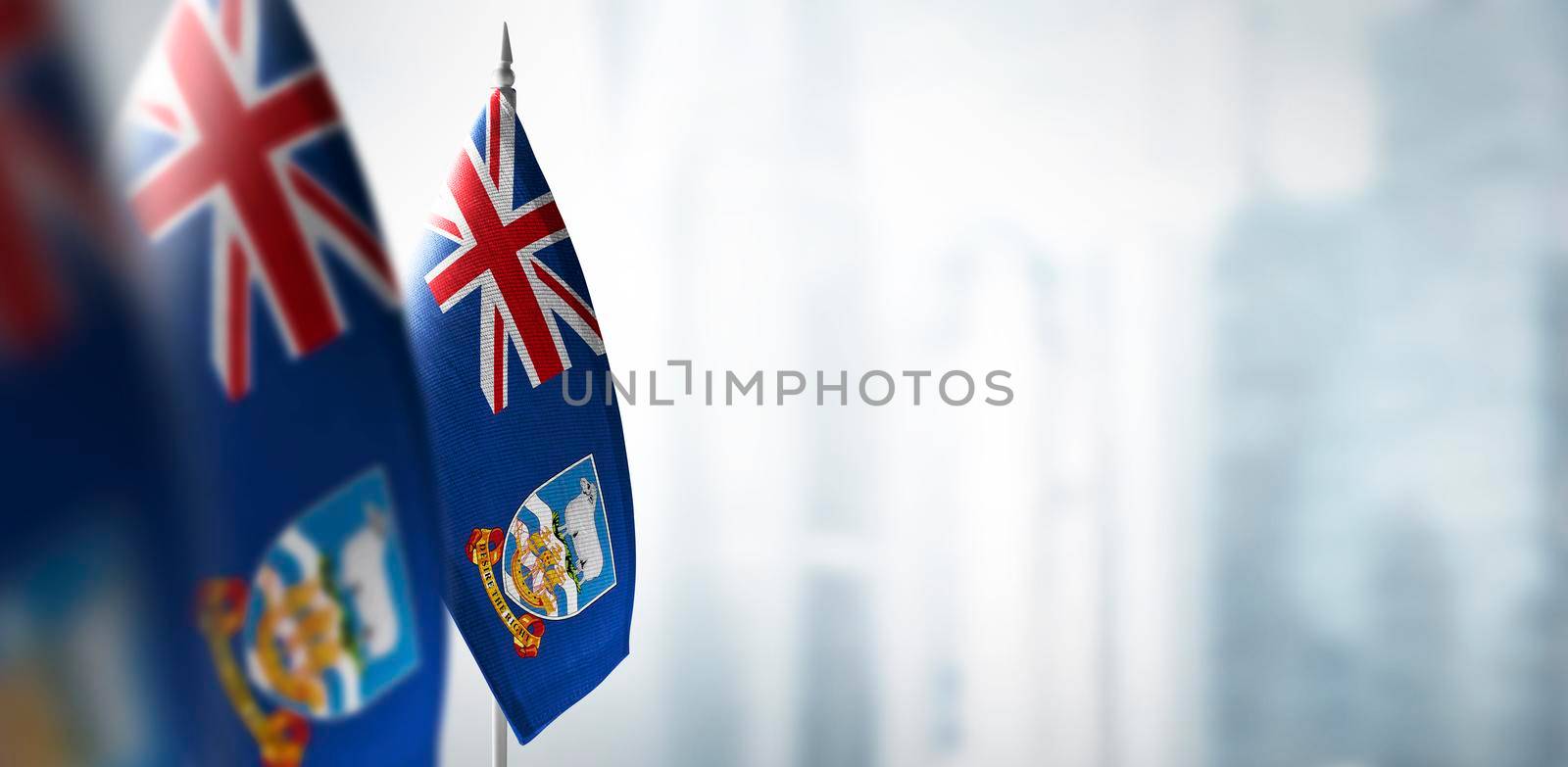 Small flags of Falkland Islands on a blurry background of the city.