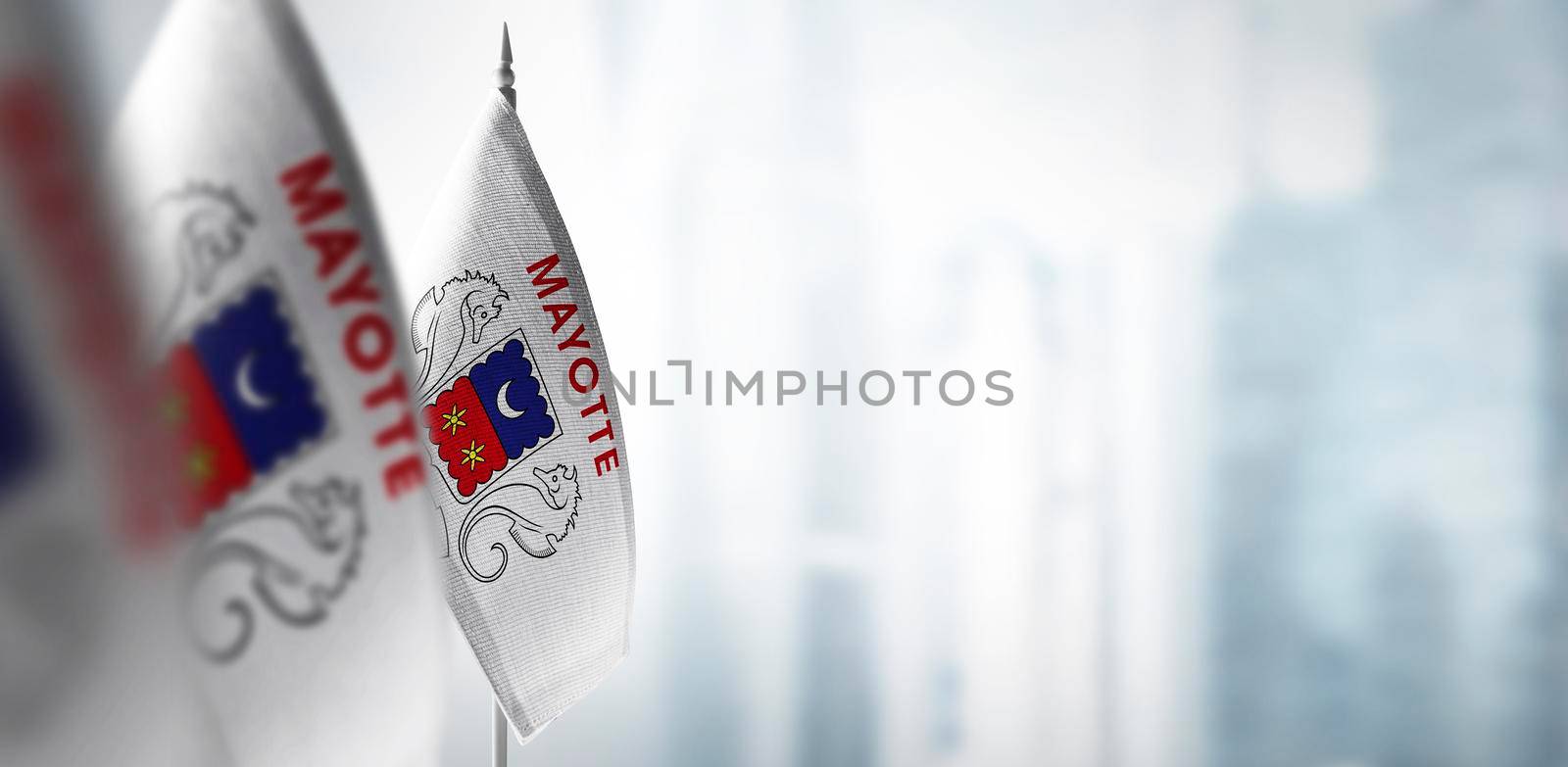 Small flags of Mayotte on a blurry background of the city.