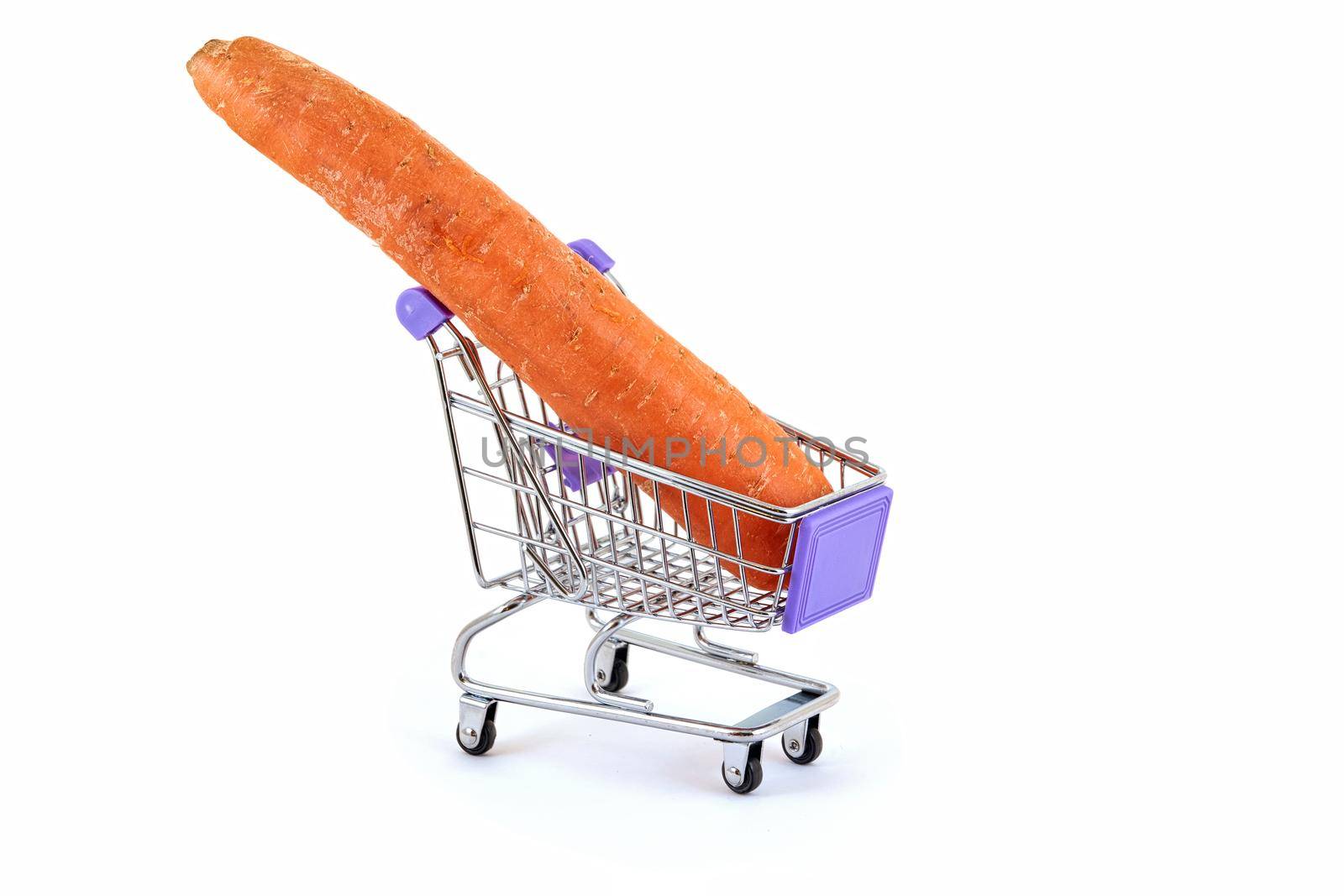 A long red carrot lies in a small supermarket trolley on a white background, close up