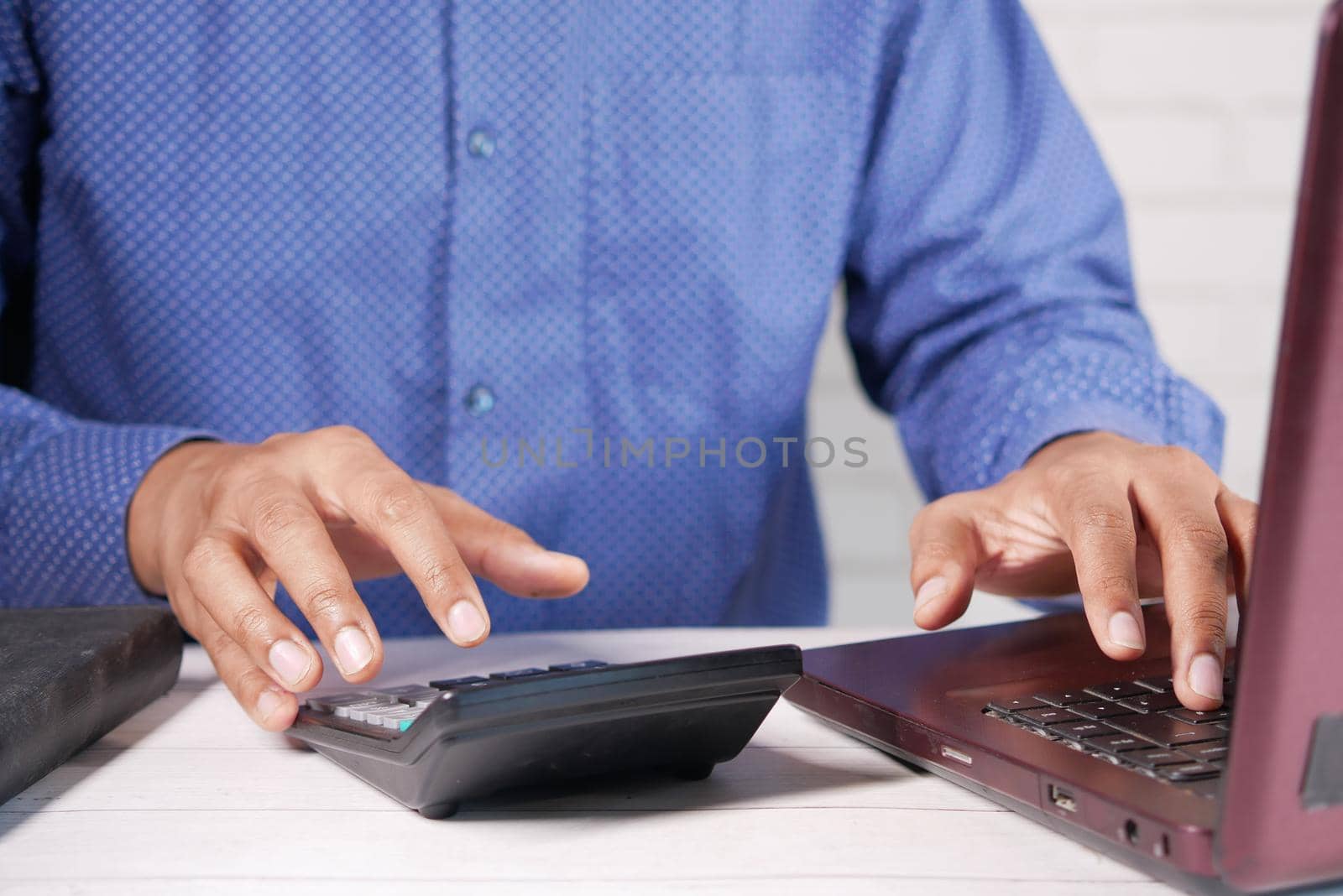 Close up of man hand using calculator.