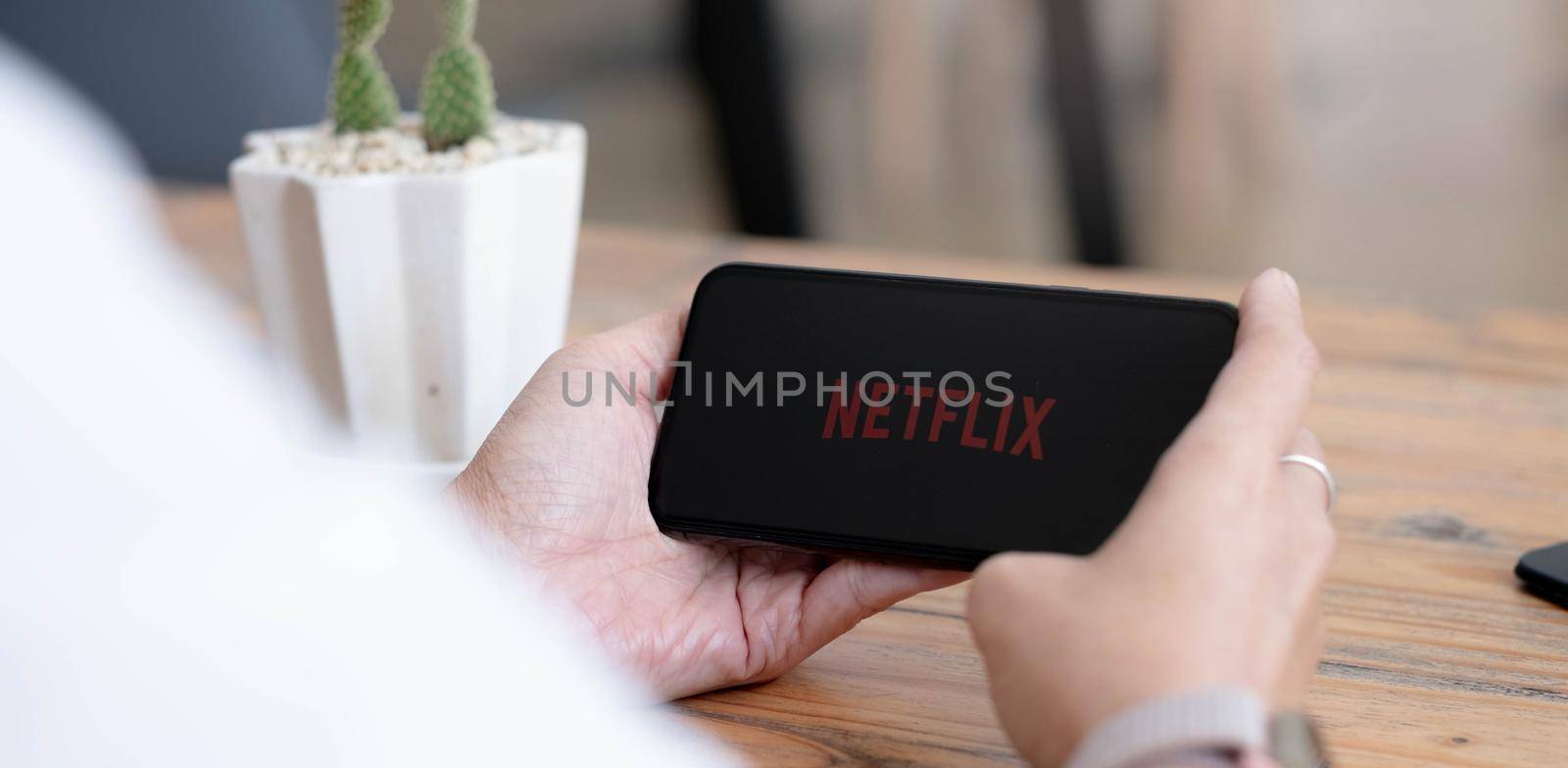CHIANG MAI, THAILAND, AUG 2 2021 : Woman hand holding Smart Phone with Netflix logo on Apple iPhone Xs. Netflix is a global provider of streaming movies and TV series. by wichayada