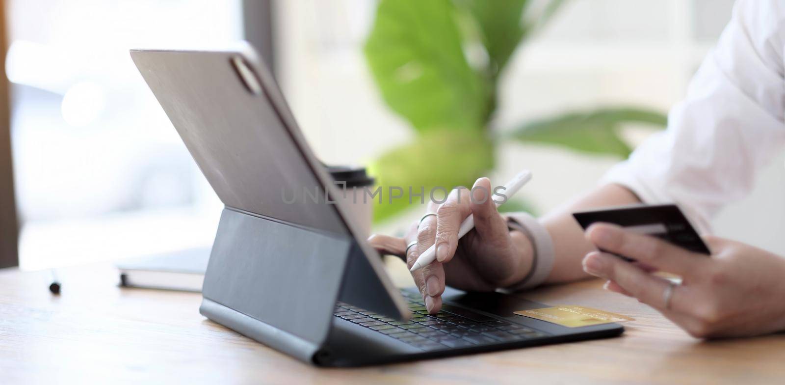 Close up woman hand using credit card and smartphone laptop for buying online shopping by wichayada