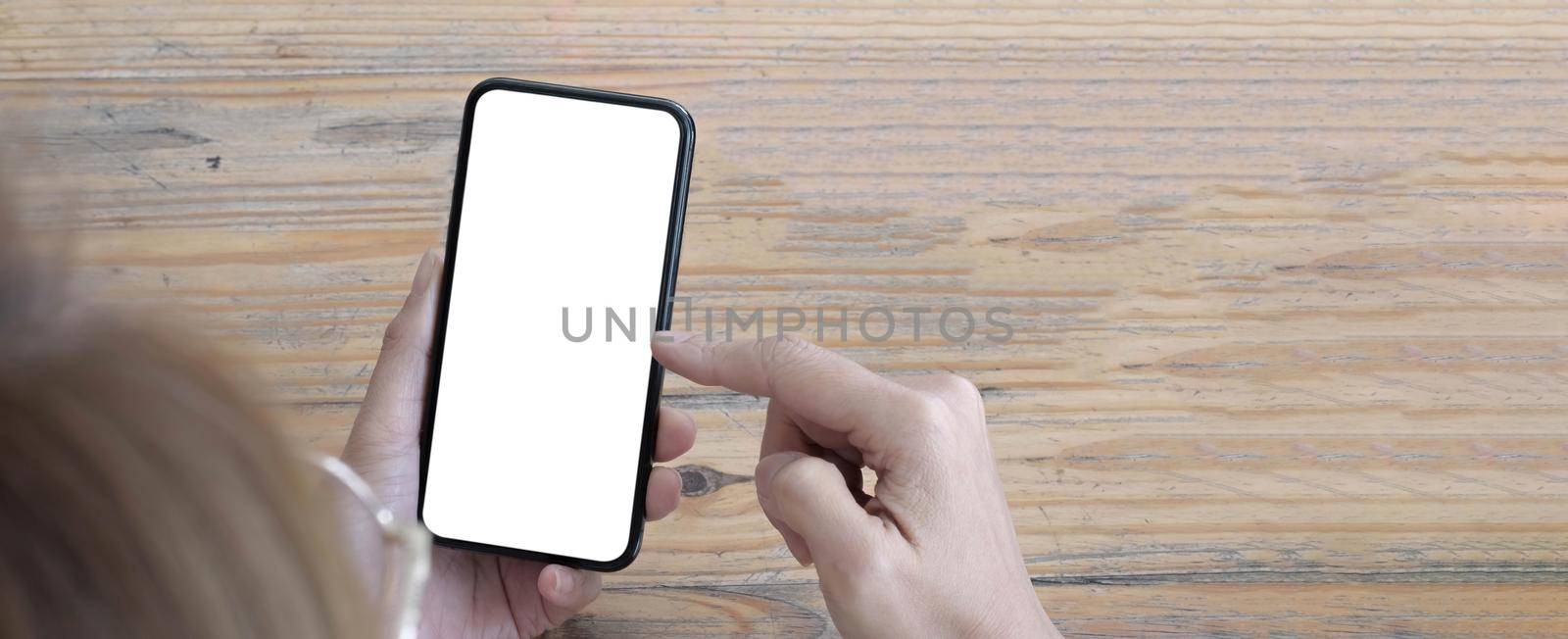 Mockup image blank white screen cell phone.women hand holding texting using mobile on desk at home office..