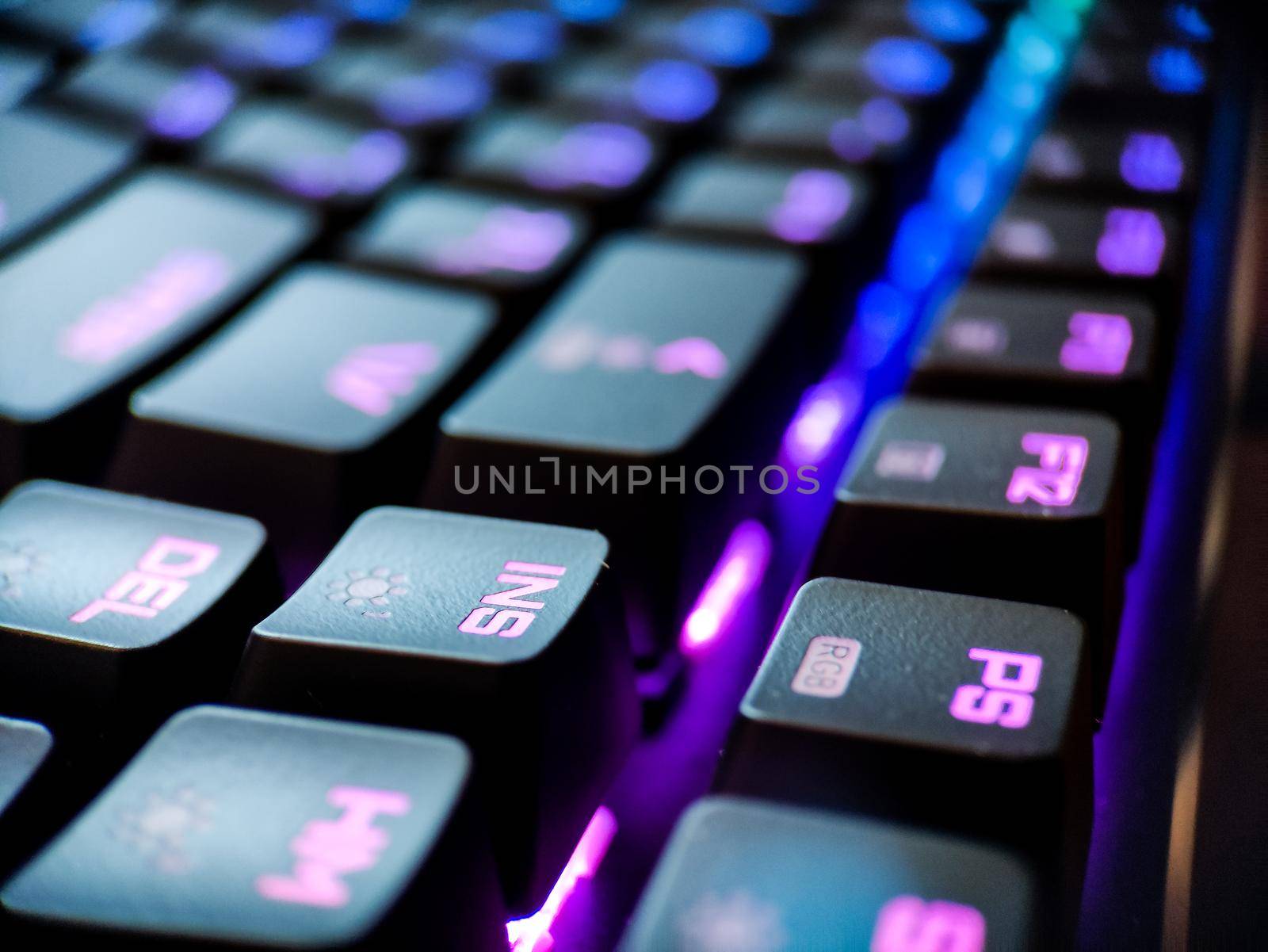 Gamer keyboard with neon backlight macro defocused close up. Online games and virtual reality concept background. High quality photo