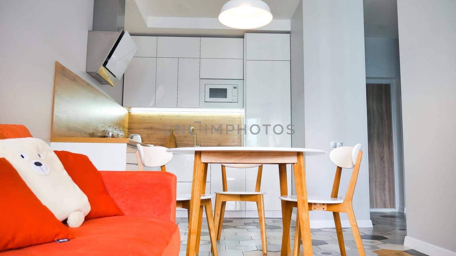 Modern kitchen interior with wooden and white elements, bright orange sofa, domestic life, home showcase interior concept. by balinska_lv