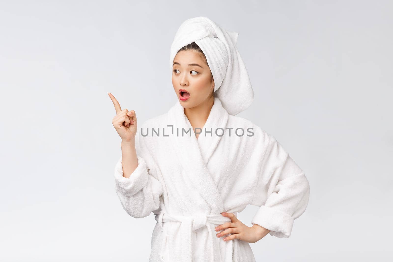 Beauty portrait of young woman showing and pointing finger to empty copy space, asian beauty in bathrobe