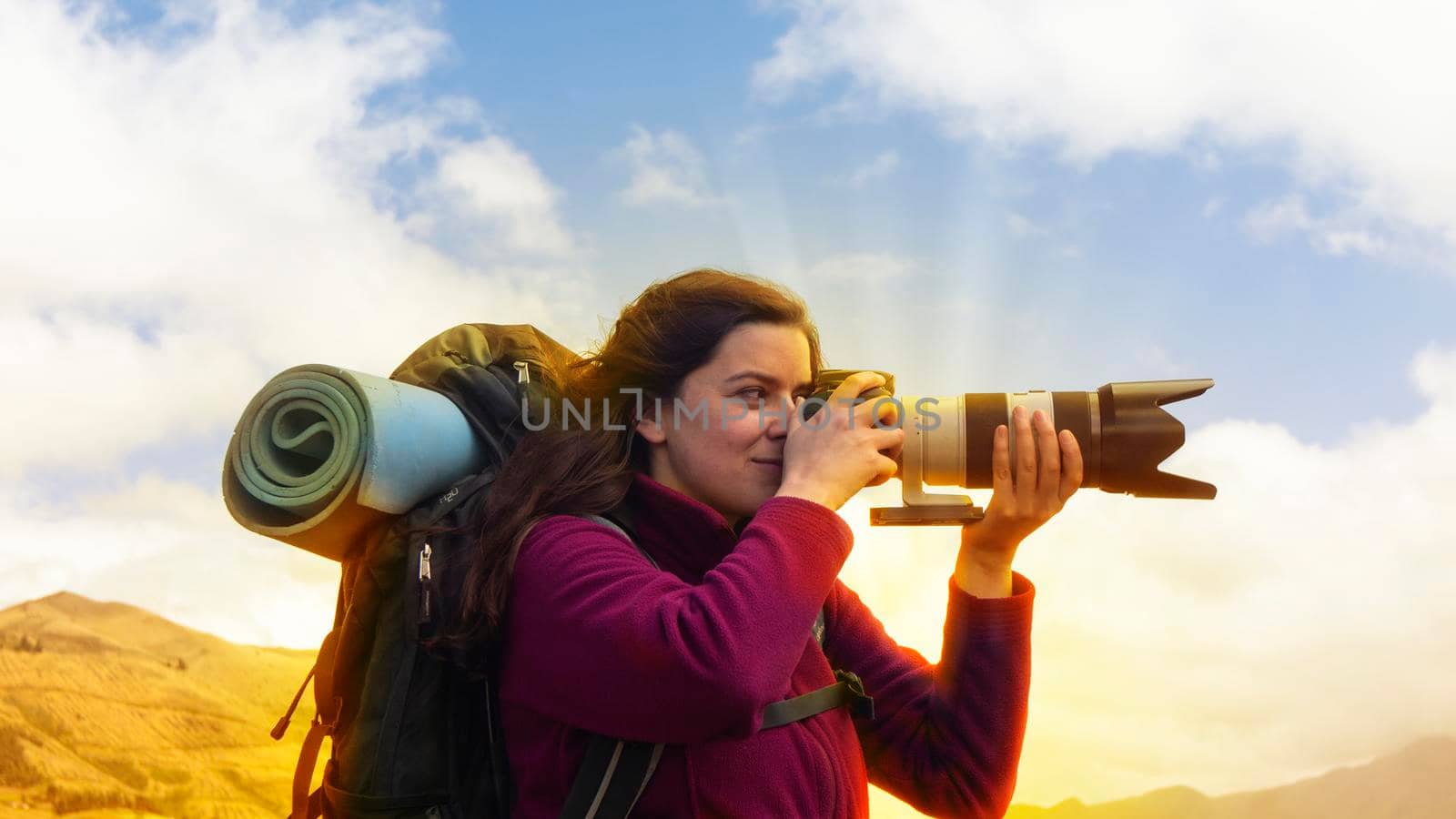 Close up of a beautiful Hispanic female scout with a backpack taking a photo with a telephoto lens on a morning