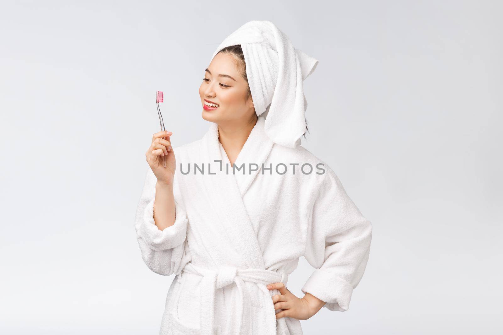 Asian happy woman with toothbrush in bathrobe morning mood.