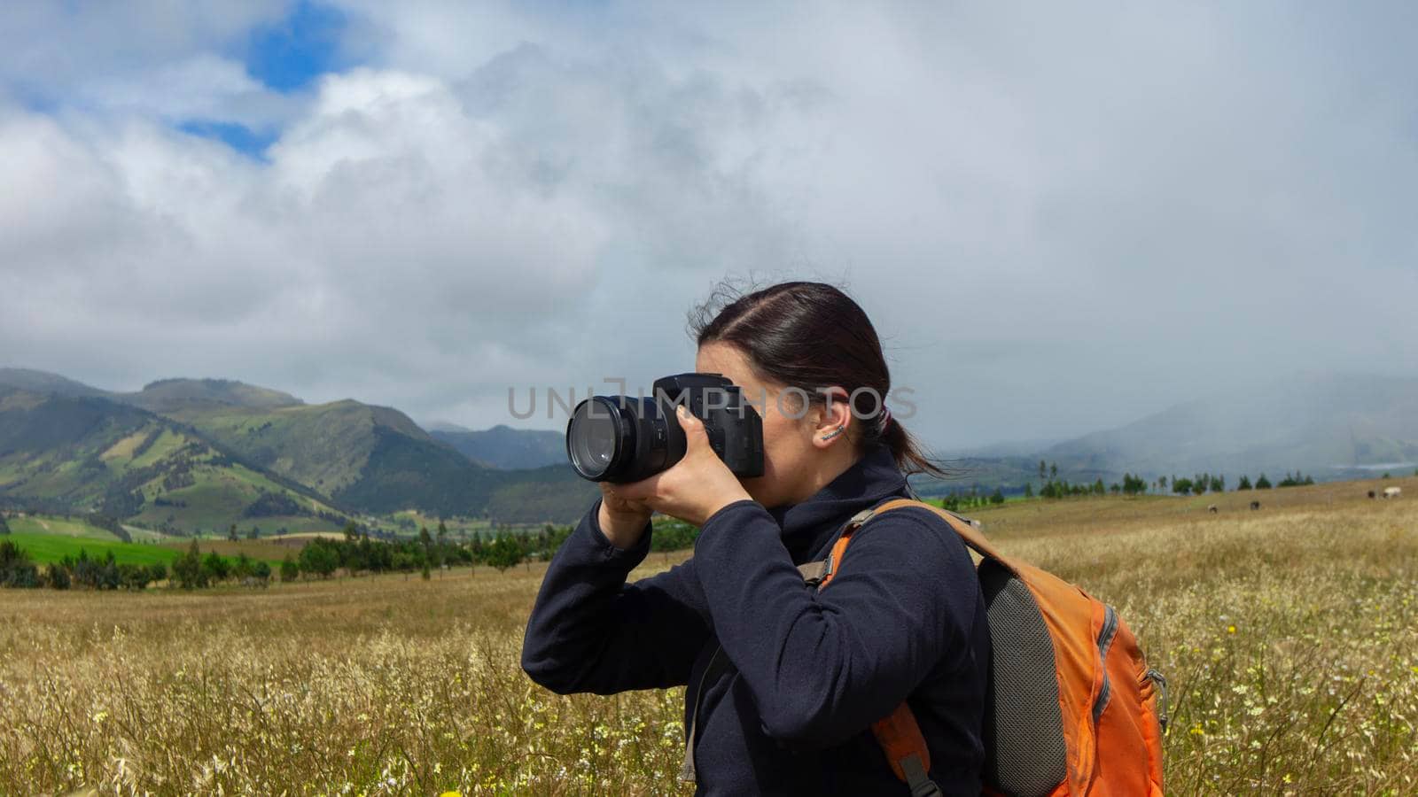 Close up of a beautiful Hispanic female scout with a backpack taking a picture in the middle of a sown field by alejomiranda