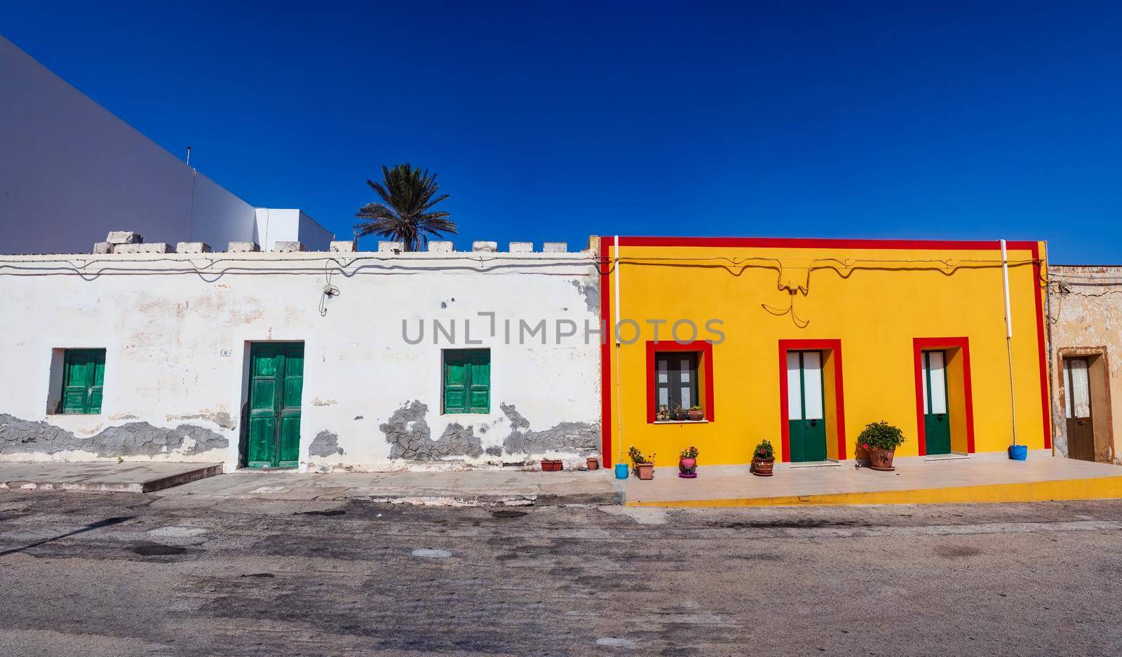 View of a typical colorful house of Linosa, colored with white, red and orange with green door