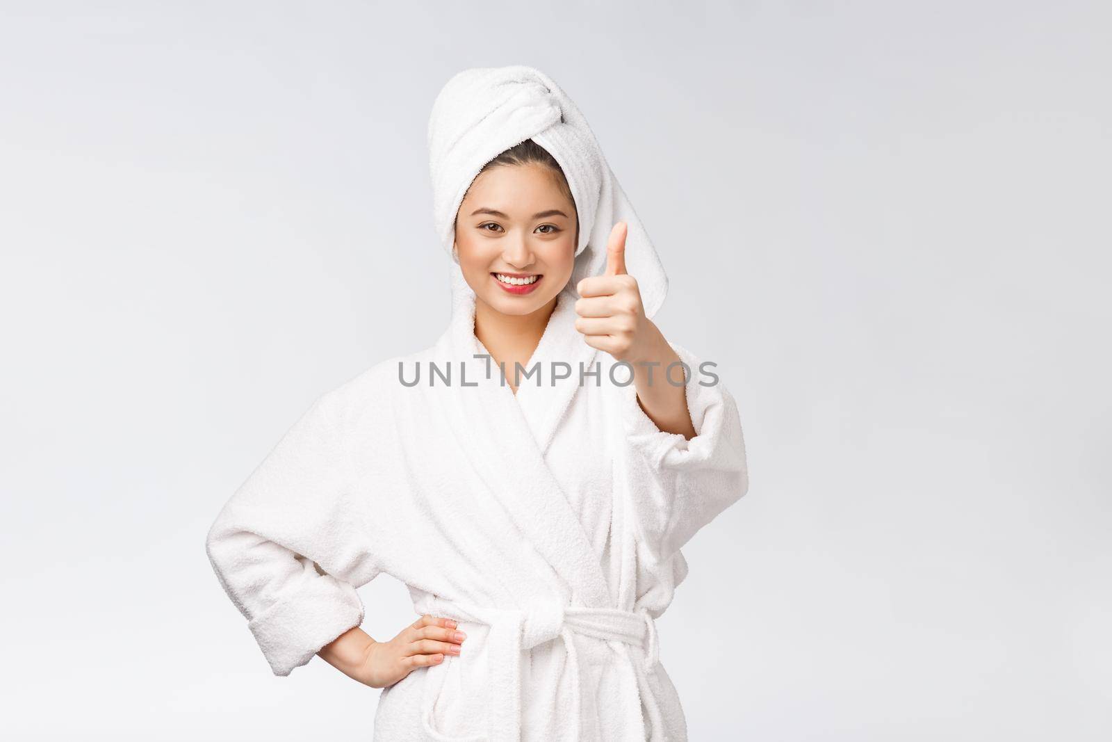 Beautiful asian woman perfect skin showing thumbs up isolated on white background. by Benzoix