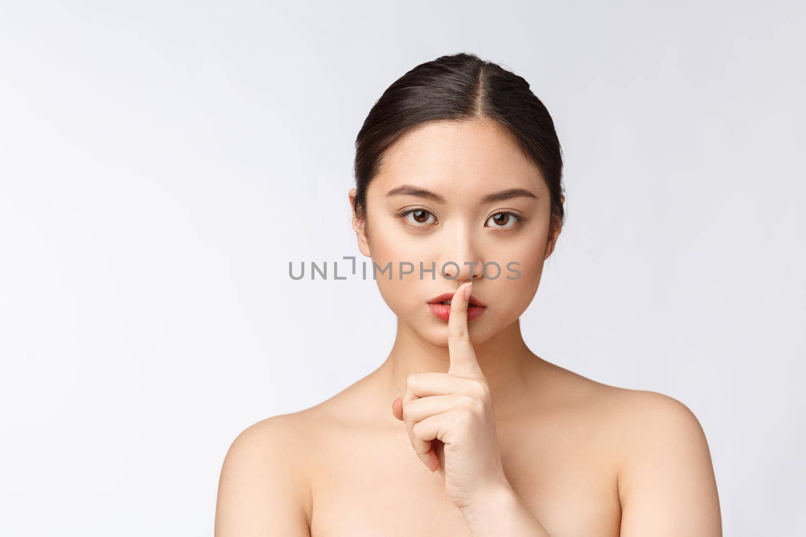 Portrait of asian woman making a hush gesture with finger on lips, isolated on white background.