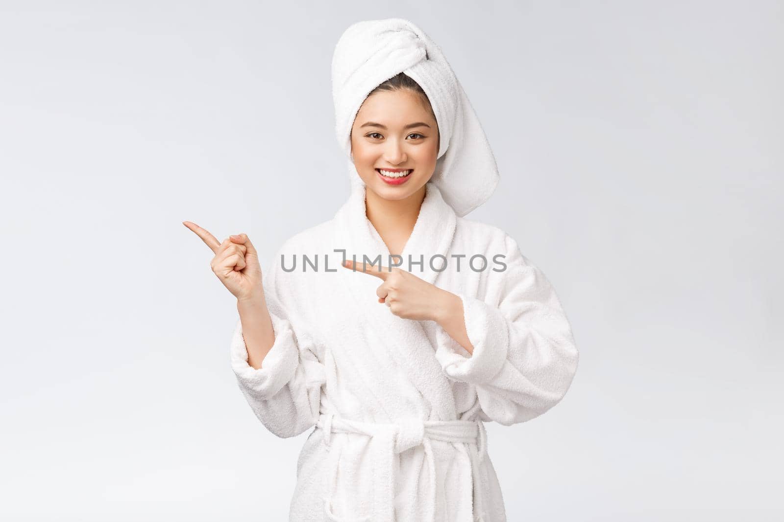 Beauty portrait of young woman showing and pointing finger to empty copy space, asian beauty in bathrobe. by Benzoix