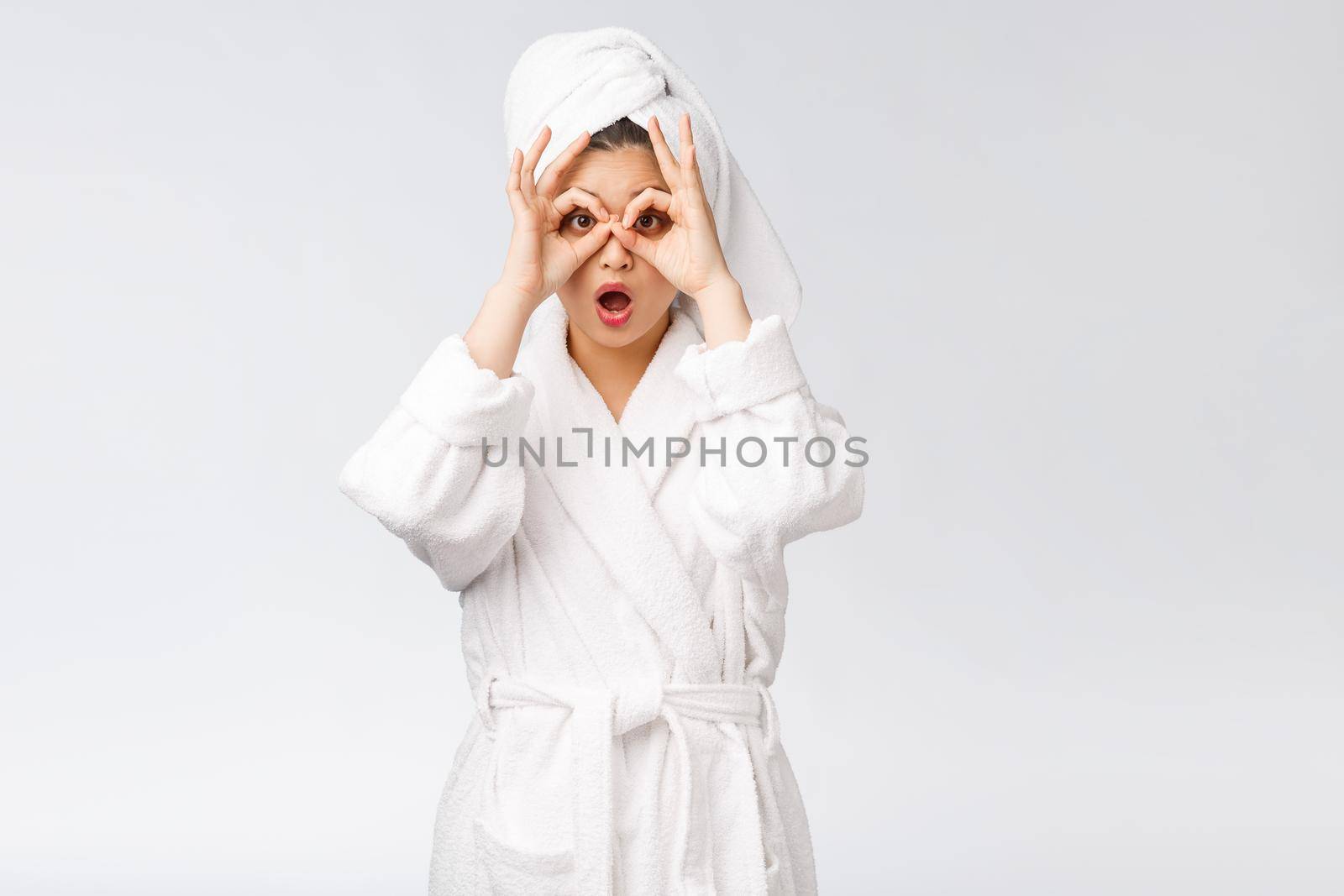 Close up of young smiling woman with finger ok gesture on eyes, isolated on white background.