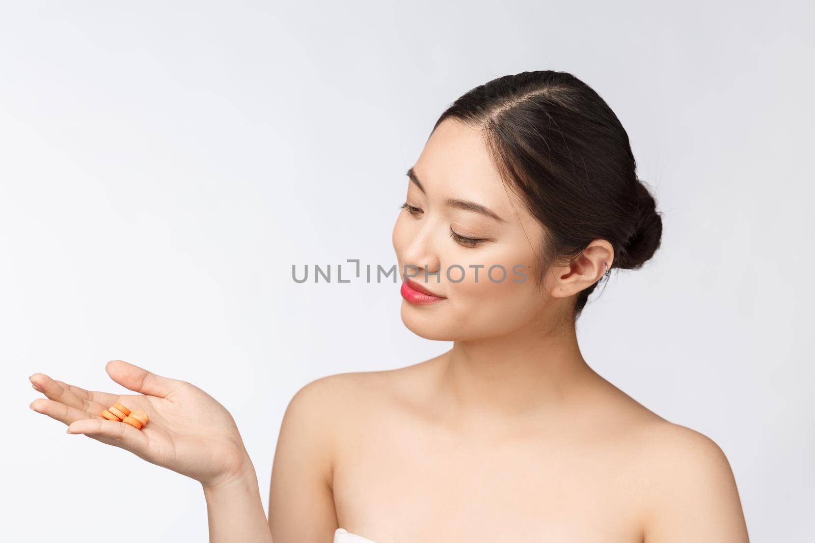 Young attractive asian woman who takes a capsule or pill. Isolated over white background