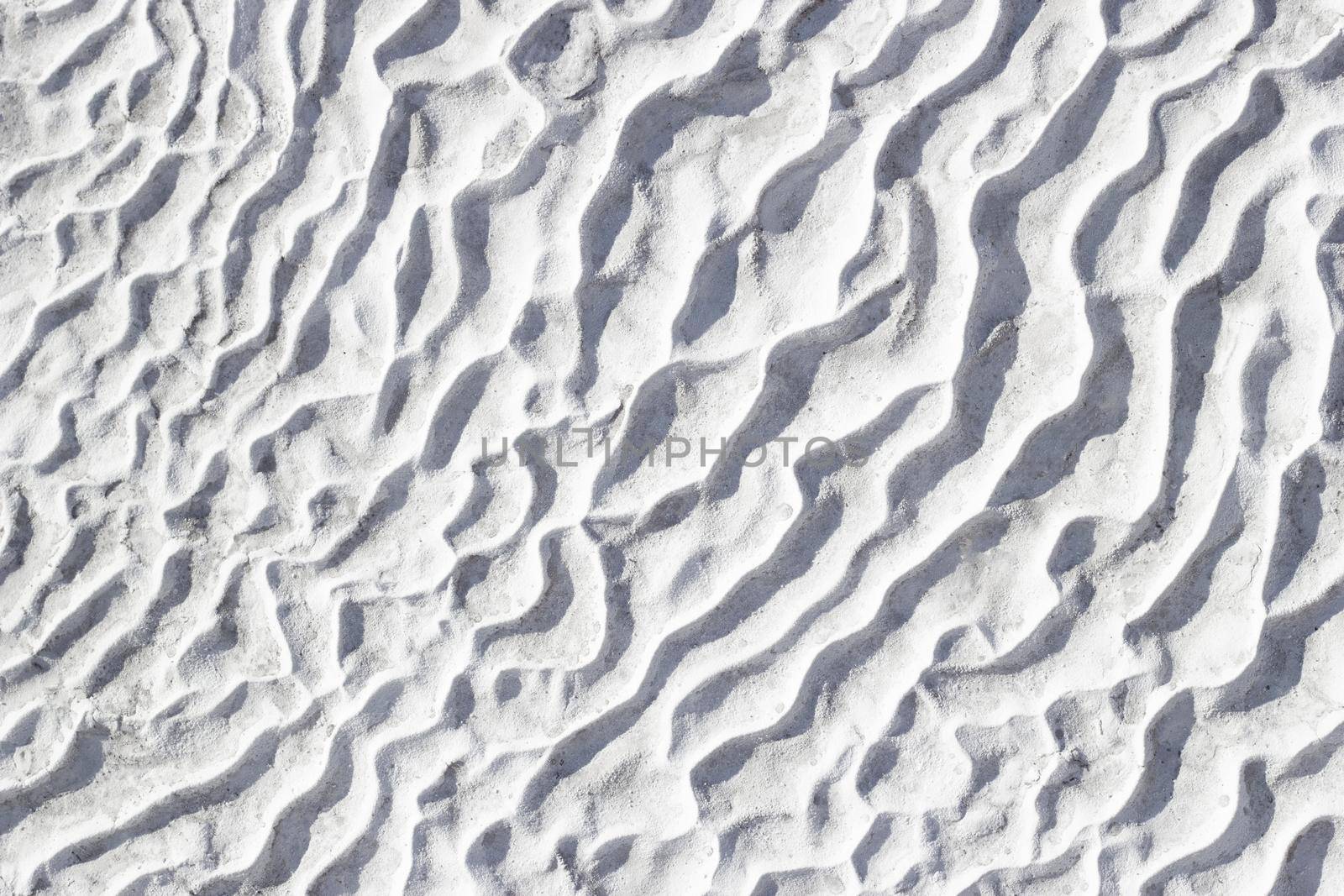 Gray texture background of Pamukkale calcium travertine in Turkey, pattern of diagonal waves, close-up.