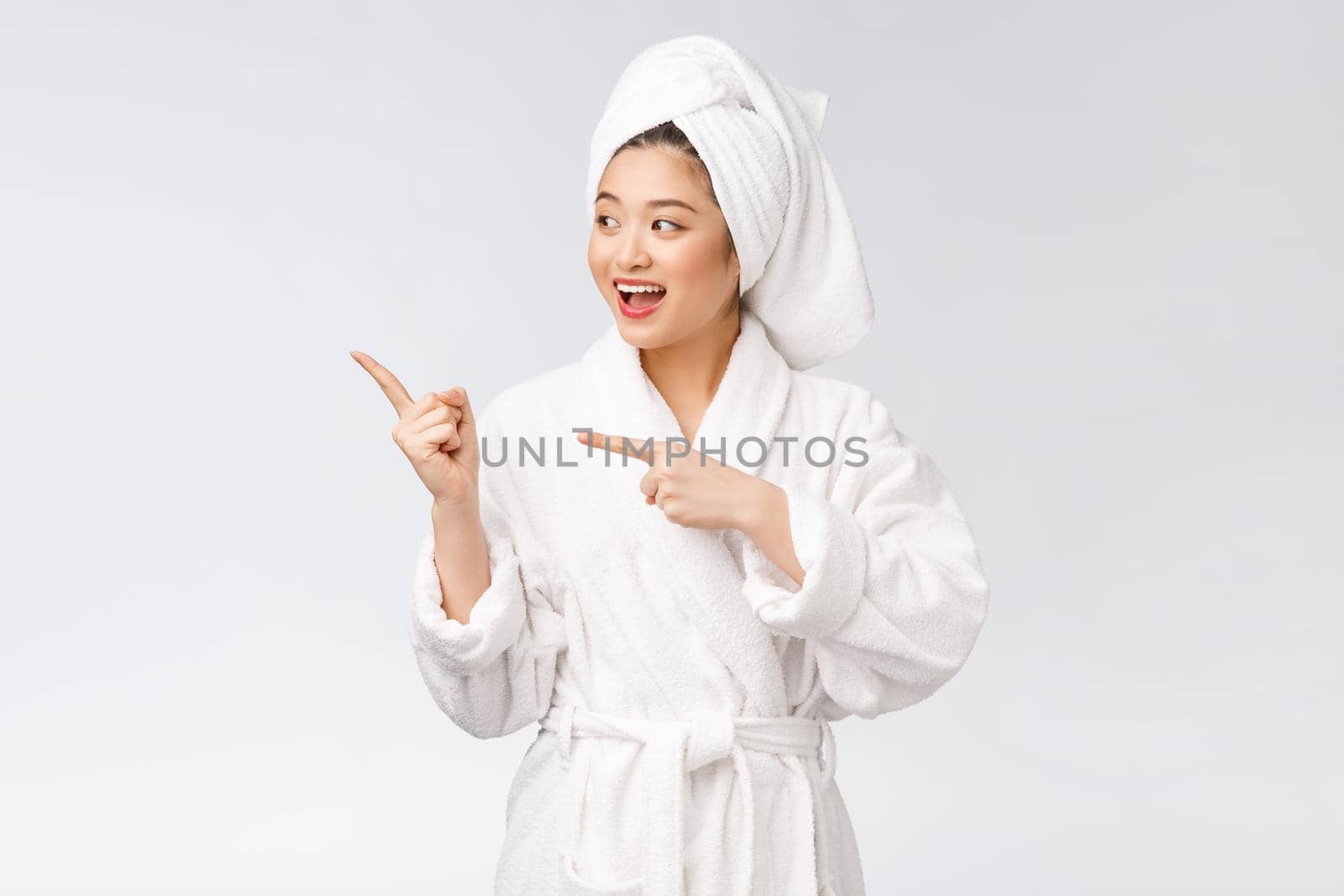 Beauty portrait of young woman showing and pointing finger to empty copy space, asian beauty in bathrobe