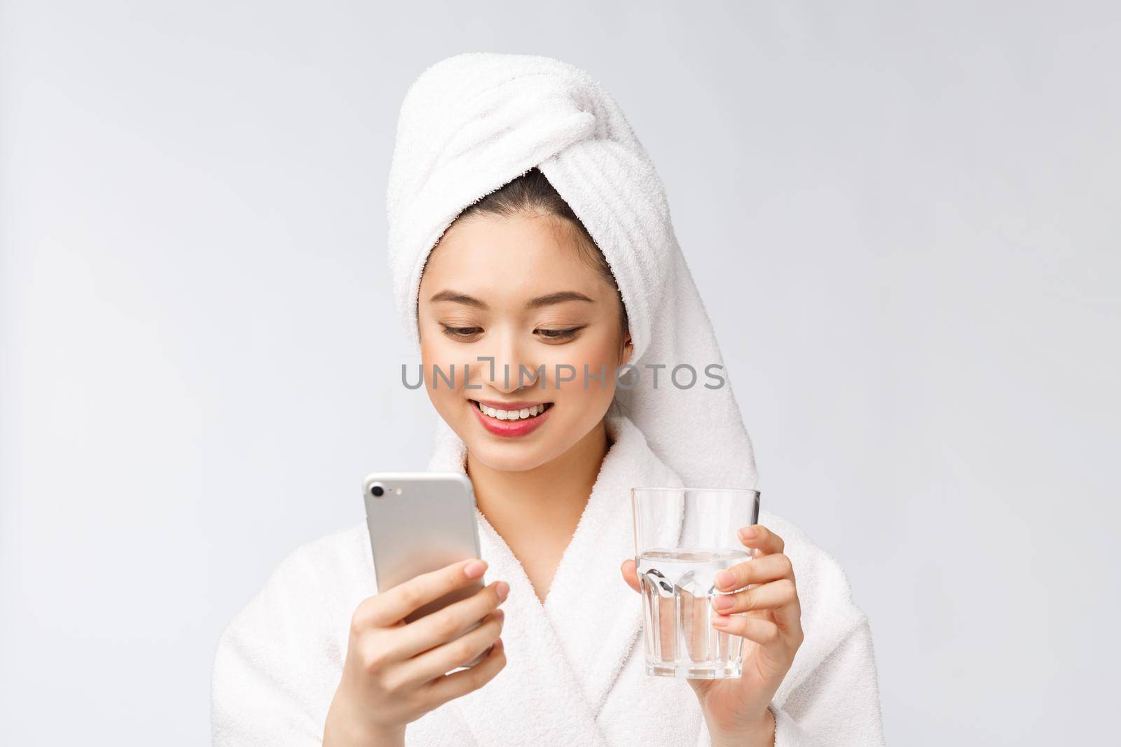 Healthy young beautiful woman drinking water, beauty face natural makeup with holding mobile phone, isolated over white background