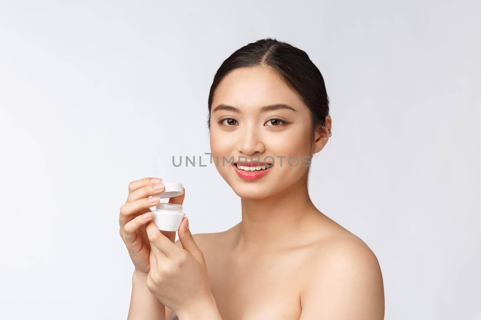 Beautiful young woman on white isolated background holding cosmetic face cream, asian by Benzoix