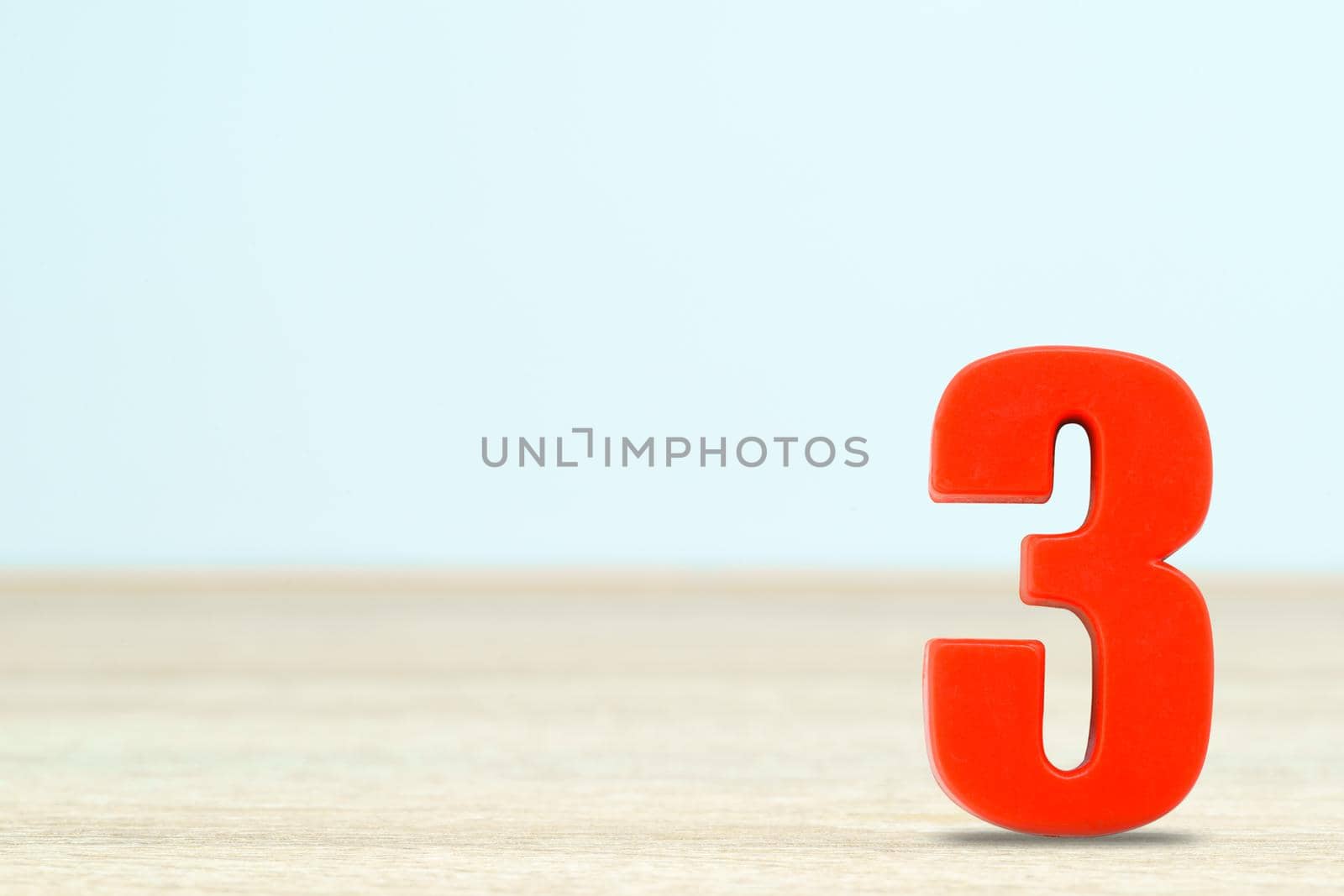 Shot of a number three made of red plastic on table with copy space
