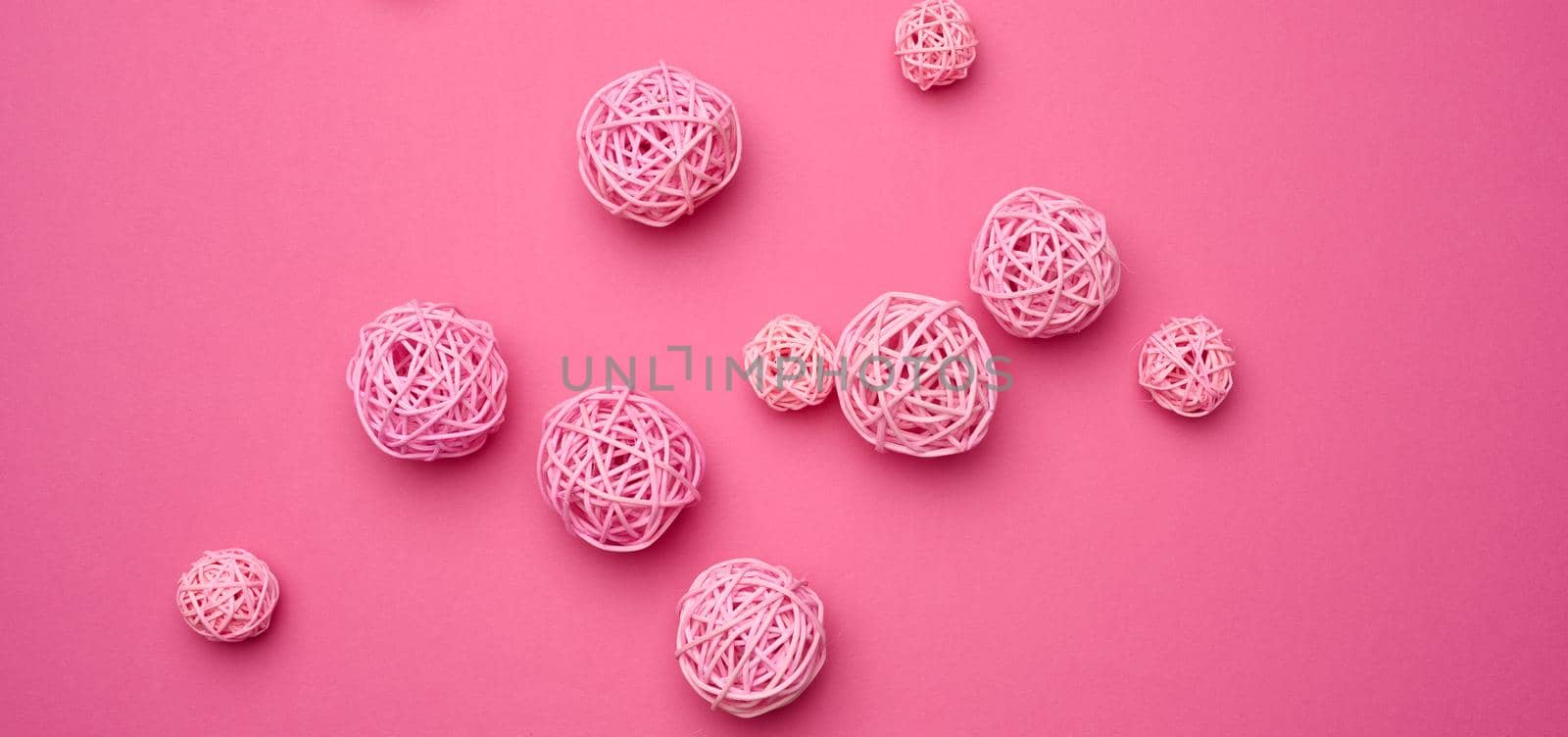 wicker wooden balls on a pink background. Decor. Abstract backdrop, top view by ndanko