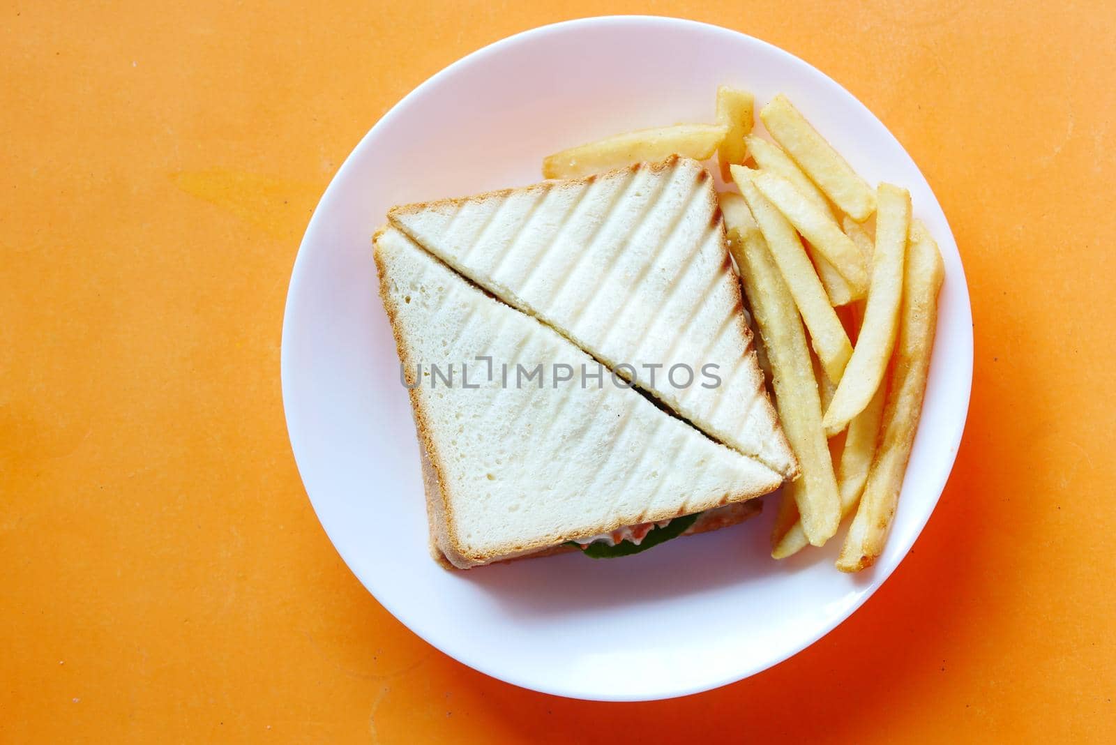 top view of chicken sandwich and chips on plate by towfiq007