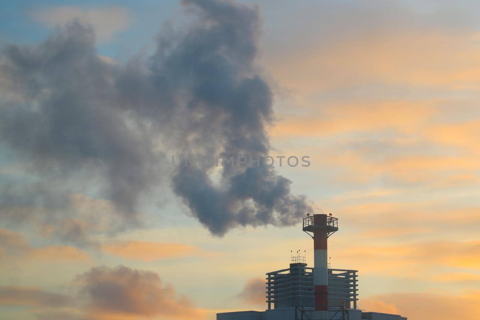 Blurred background, dark smoke coming from the production chimney