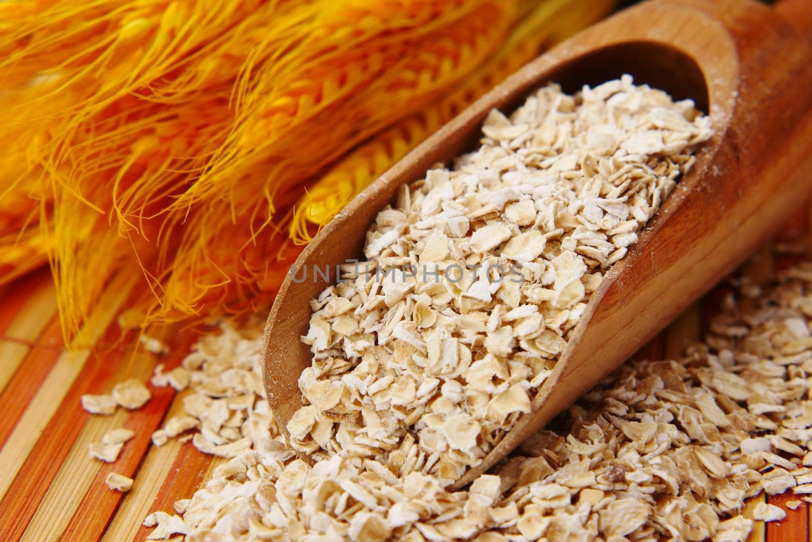 Close up of oats flakes on spoon on table .