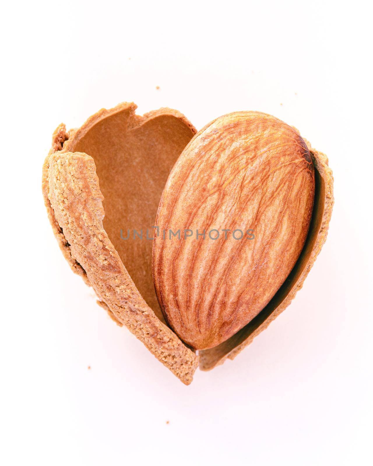 Close up almonds nut shell cracked in heart shape isolated on white background. Love healthy eating concept. by kerdkanno