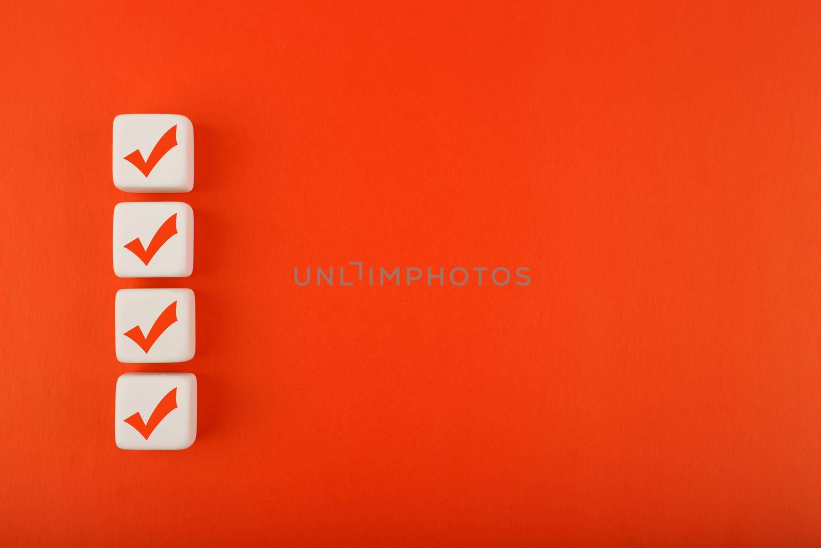 Four red checkmarks on white cubes in a row against blue background with copy space. Concept of questionary, checklist, to do list, planning, business or verification. Modern elegant flat lay