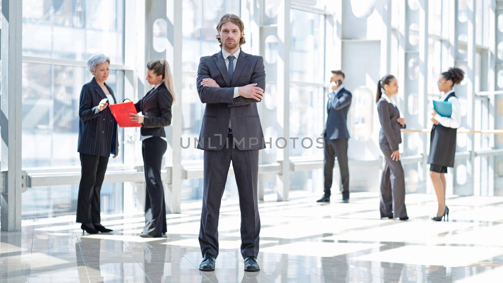 Hansome young businessman in formal suit standing in front of colleagues in business building