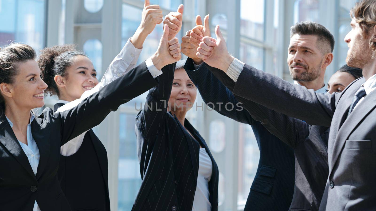 Successful business people celebrating with a thumbs up in office building lobby