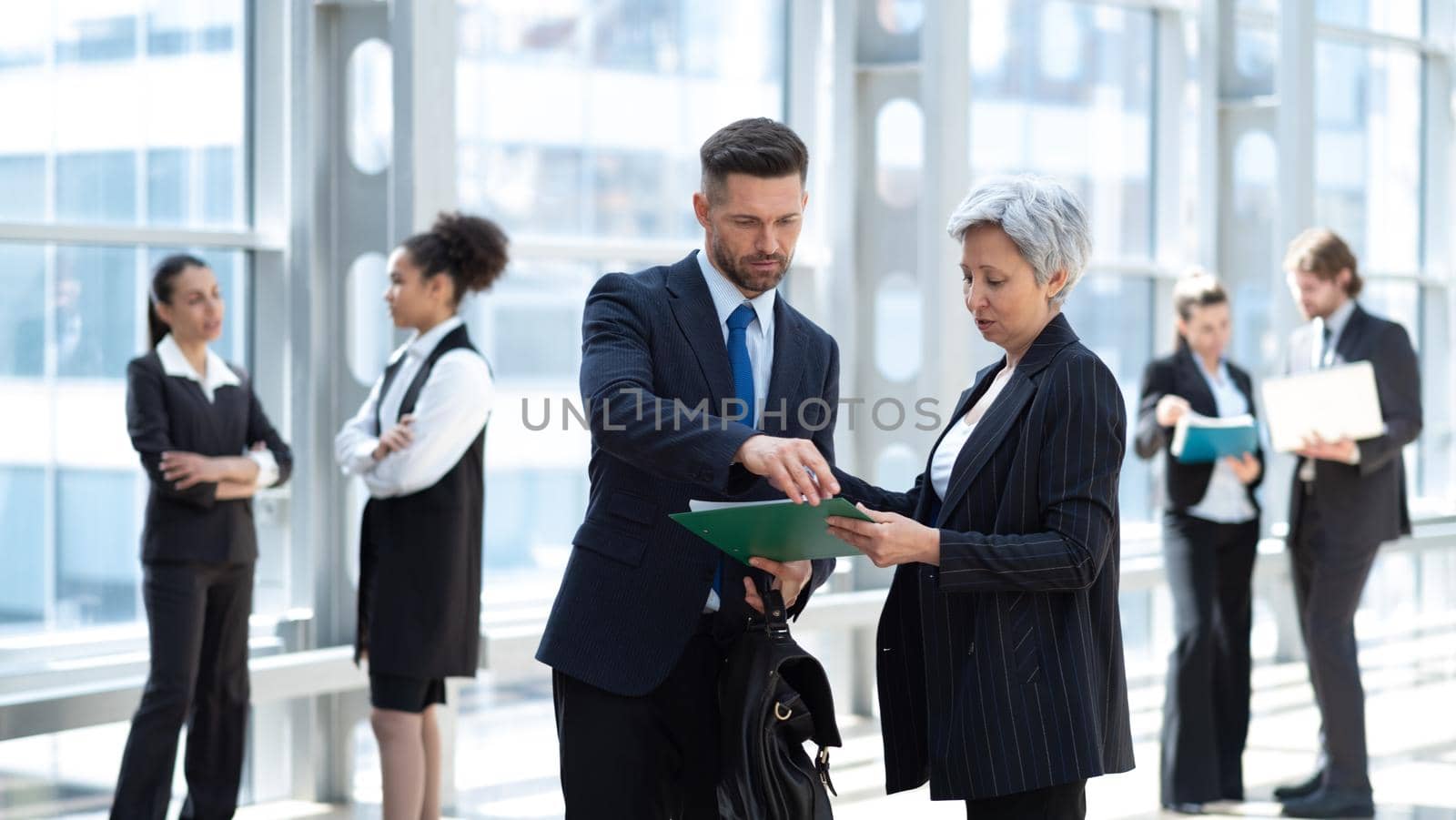 Business peopl talking about documents in office lobby of modern building