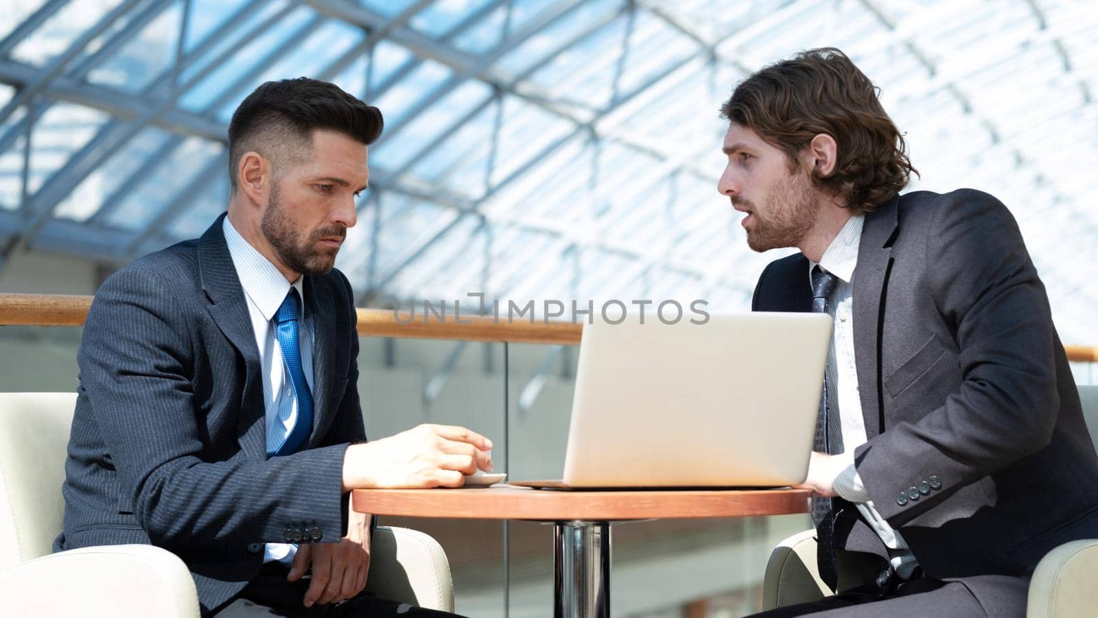 Two business men in modern office building cafe working with laptop