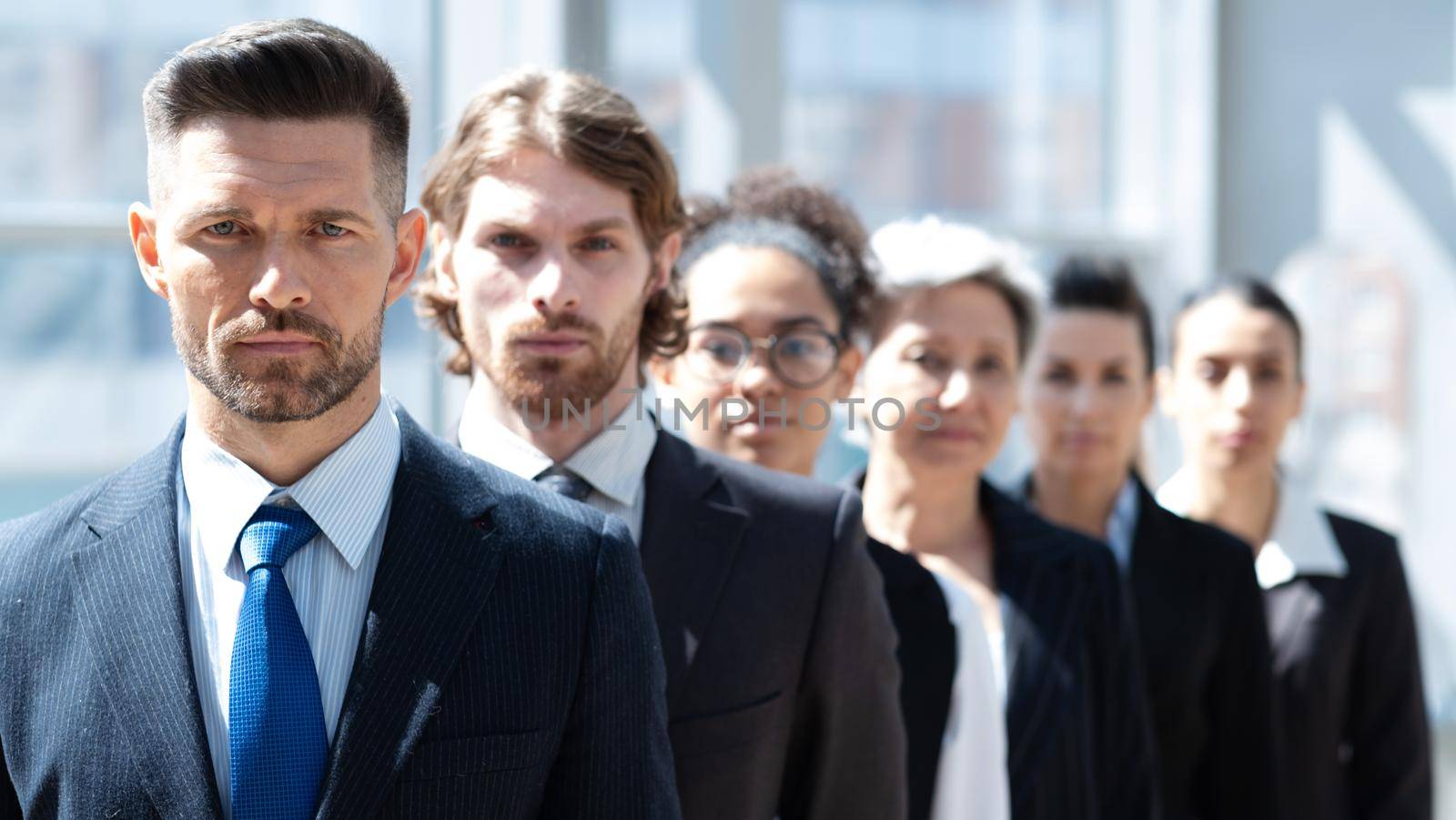 Multi ethnic group of business people standing in a row in modern office bluilding delective focus on mid adult man