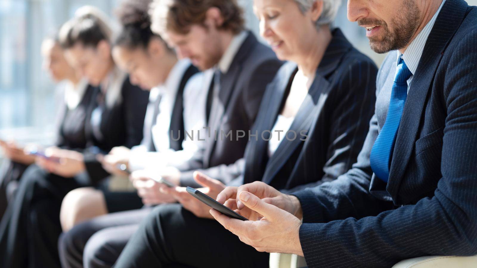 Diverse group of customers sitting in line, holding digital gadgets, using online apps and services on smartphone, laptops, tablets for work, checking messengers, chatting on social media. Banner by ALotOfPeople