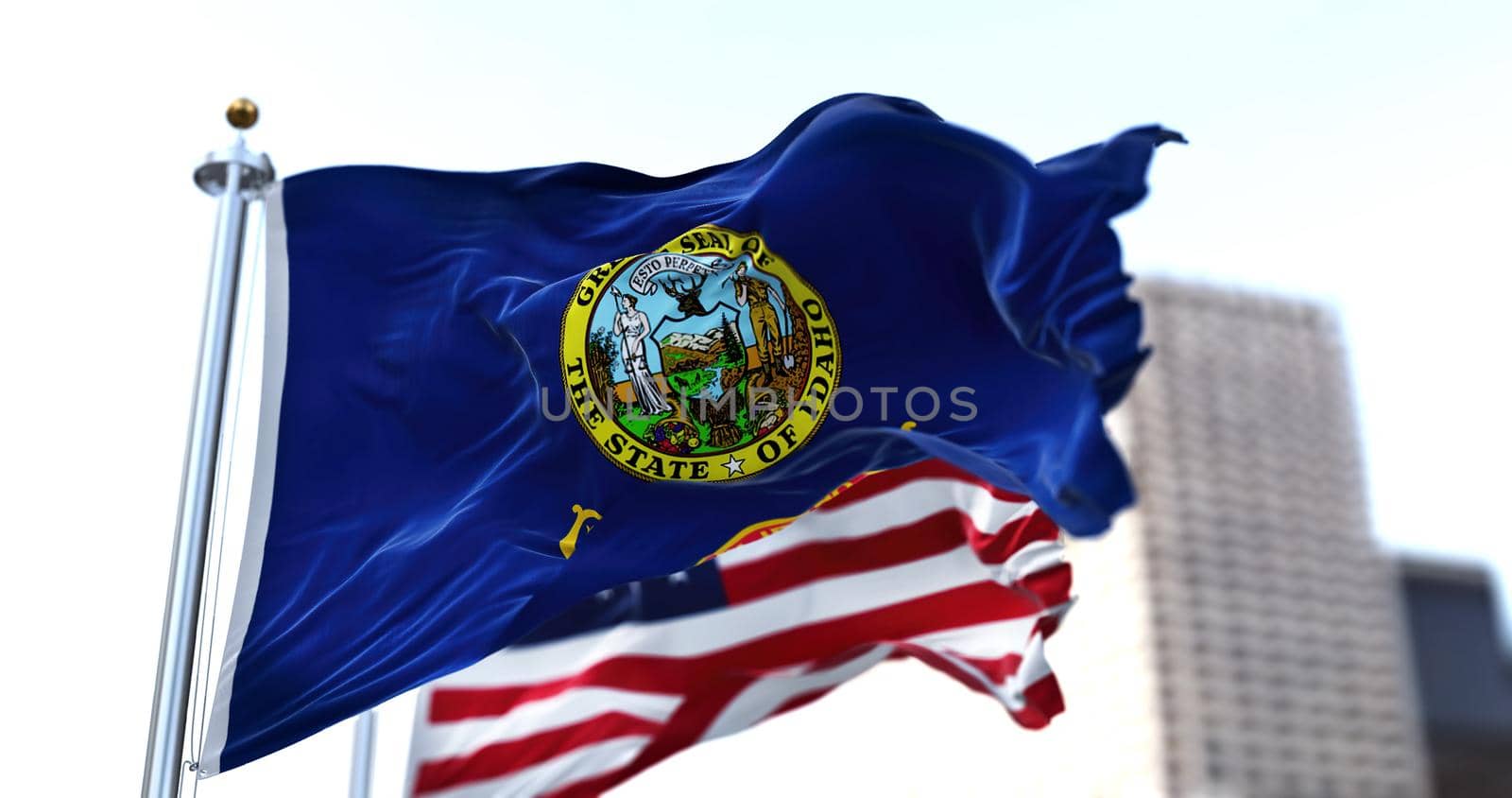 the flag of the US state of Idaho waving in the wind with the American stars and stripes flag blurred in the background. On July 3, 1890, Idaho became the 43rd state to join the Union