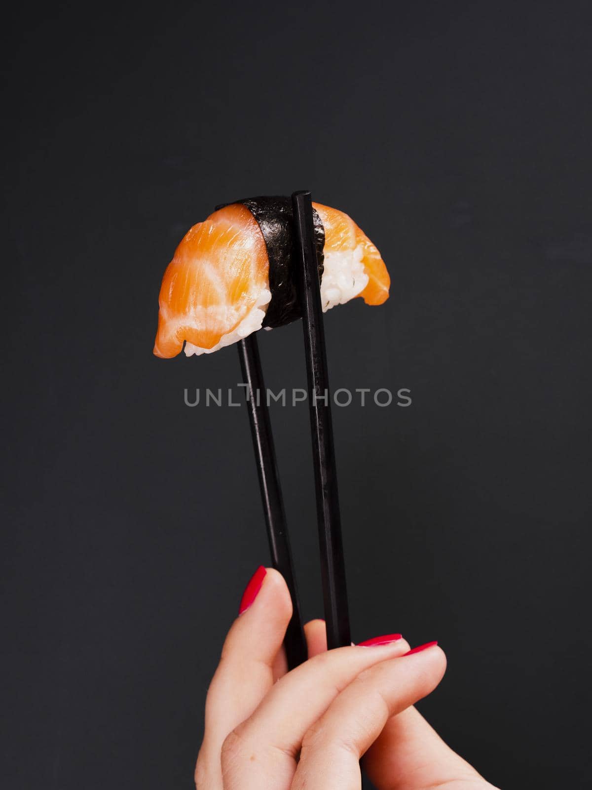 woman holding pair chopsticks with salmon sushi. High quality beautiful photo concept by Zahard