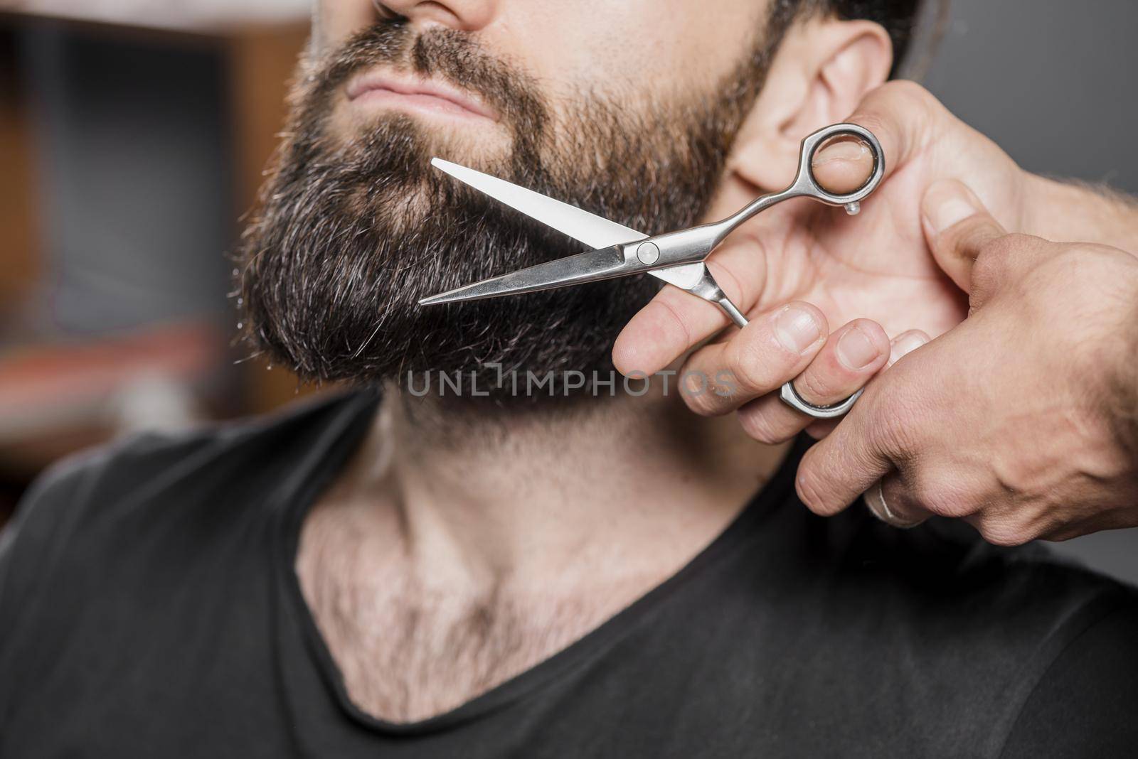 hairstylist s hand cutting man s beard with scissors. High quality beautiful photo concept by Zahard