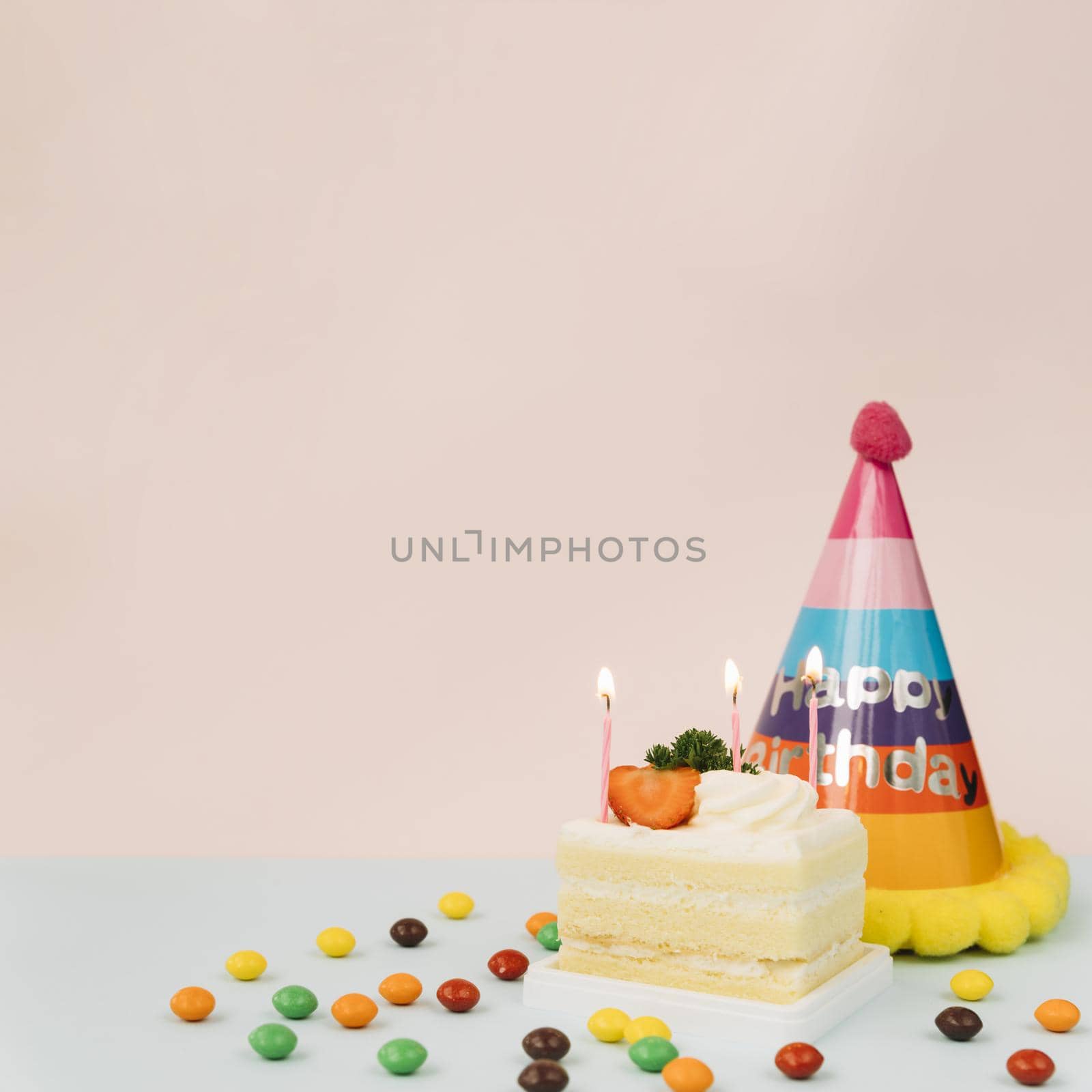 lighted candles cake candies birthday hat against colored background. High quality beautiful photo concept by Zahard