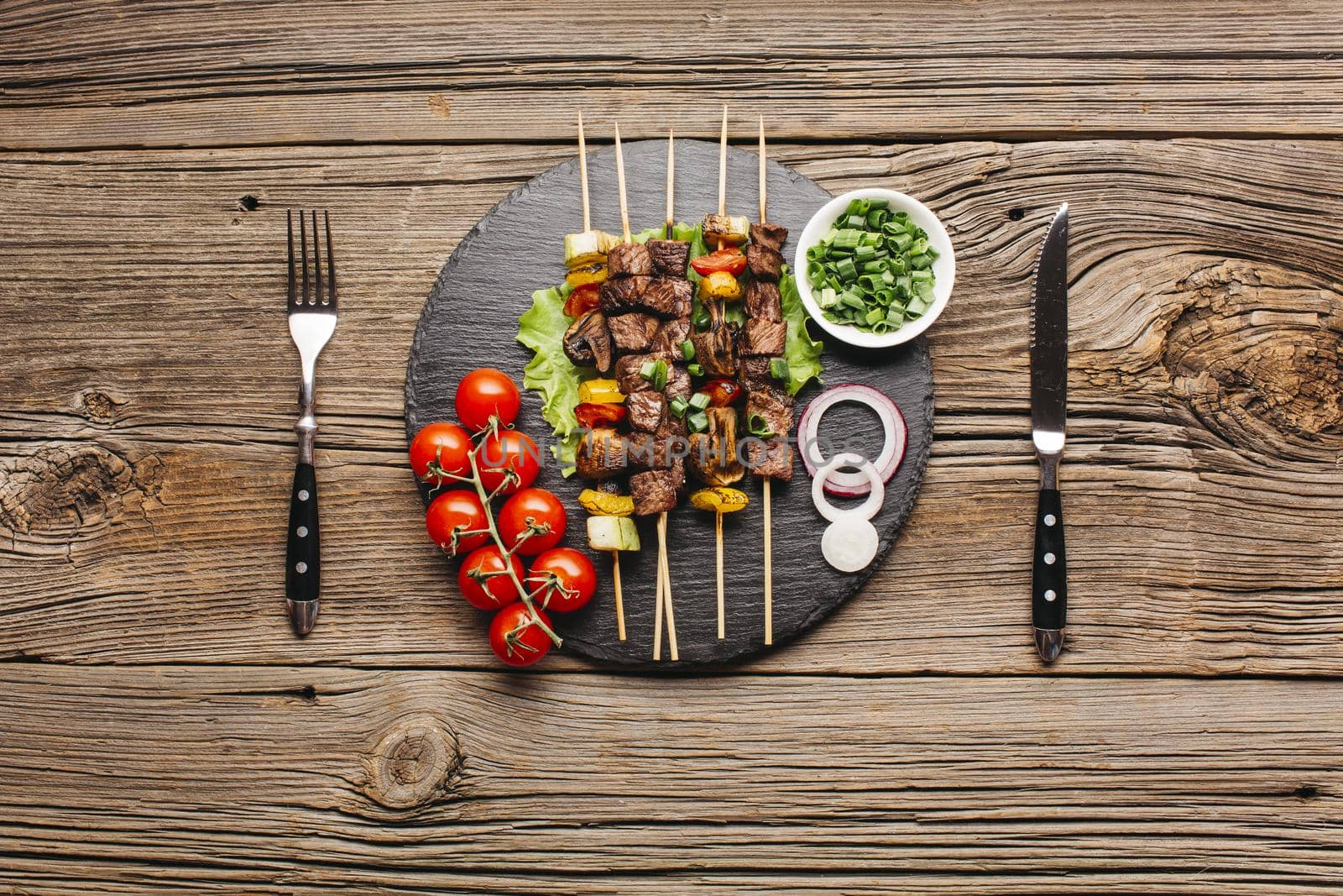 delicious meat skewer black slate with fork butter knife wooden table. High quality beautiful photo concept by Zahard