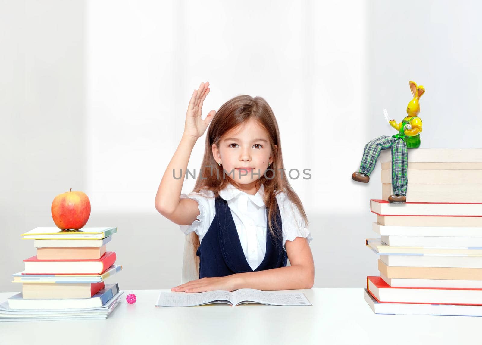 Happy and cute teen schoolgirl raising hand in classroom by Taut