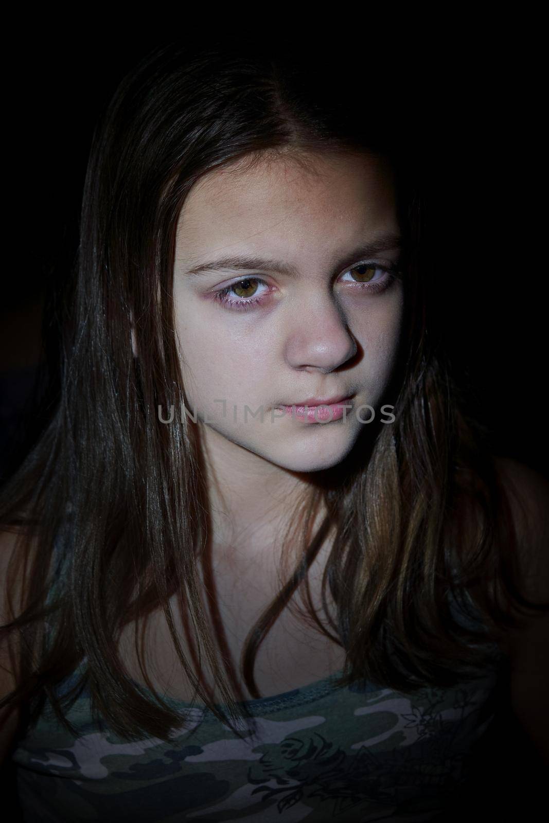 Facial portrait of cute teenage girl with long hair. Vertical shot, dark background