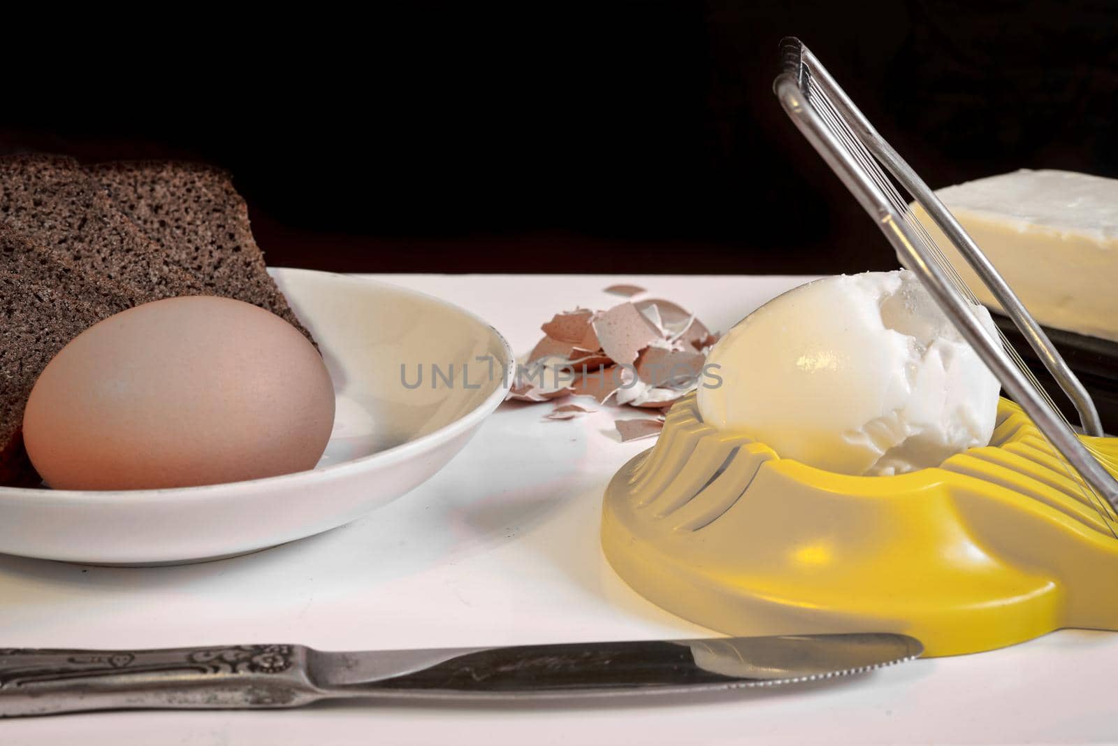 Making a breakfast sandwich, bread and butter and egg with egg on the table. Black background, close up